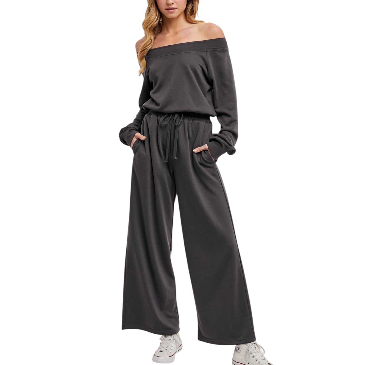 Woman wearing a gray off-shoulder jumpsuit with wide-leg pants on a white background