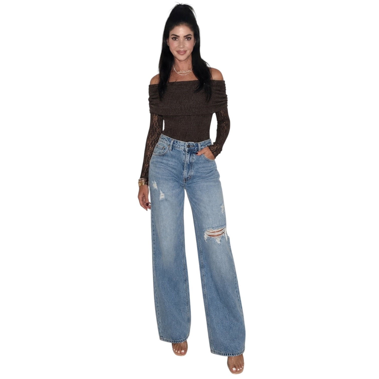 A woman modeling a dark brown off-the-shoulder long-sleeve bodysuit and light-wash distressed wide-leg jeans against a plain white background.