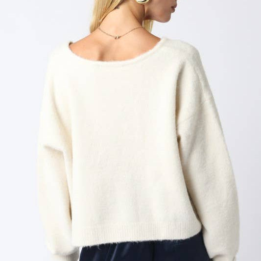 White sweater worn by a person on a plain background