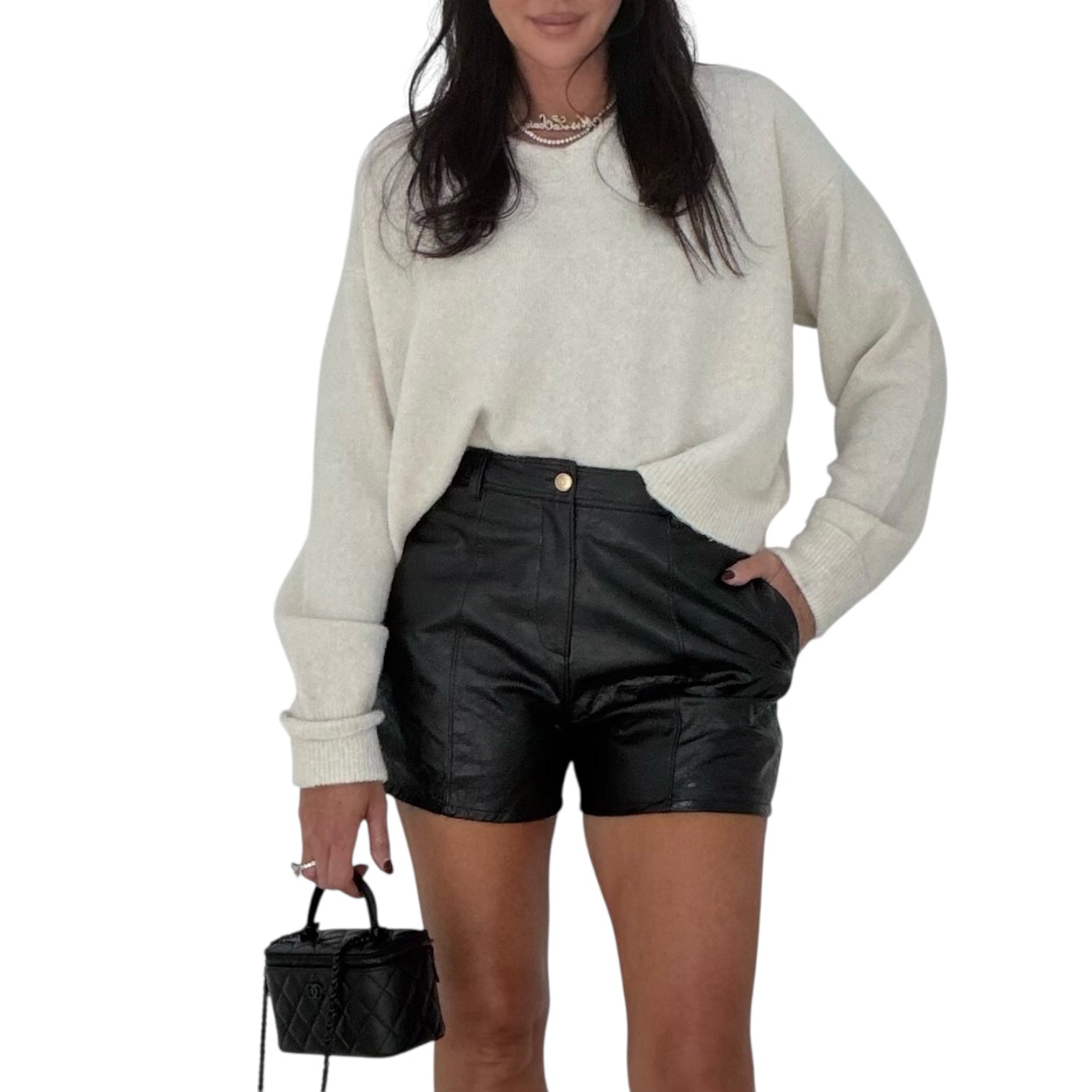 Person wearing a white sweater and black leather shorts on a white background
