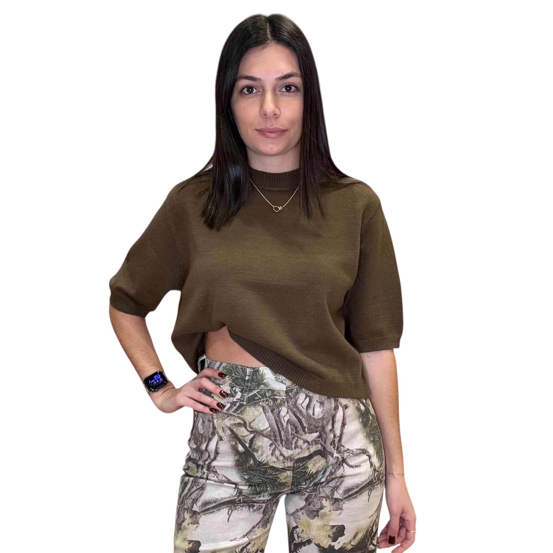 Woman wearing an olive green sweater and camouflage pants on a white background