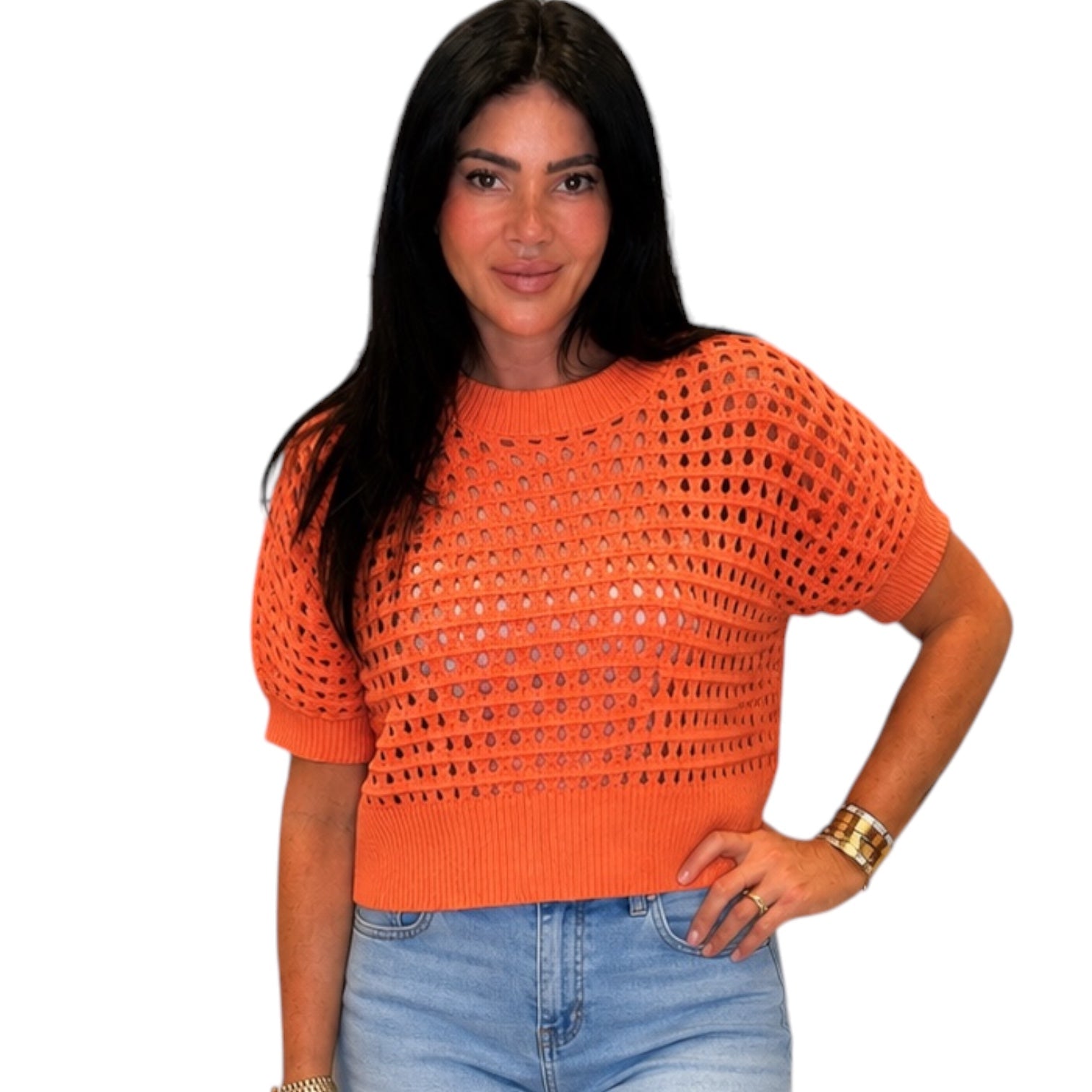 Woman wearing an orange crochet top and blue jeans on a white background