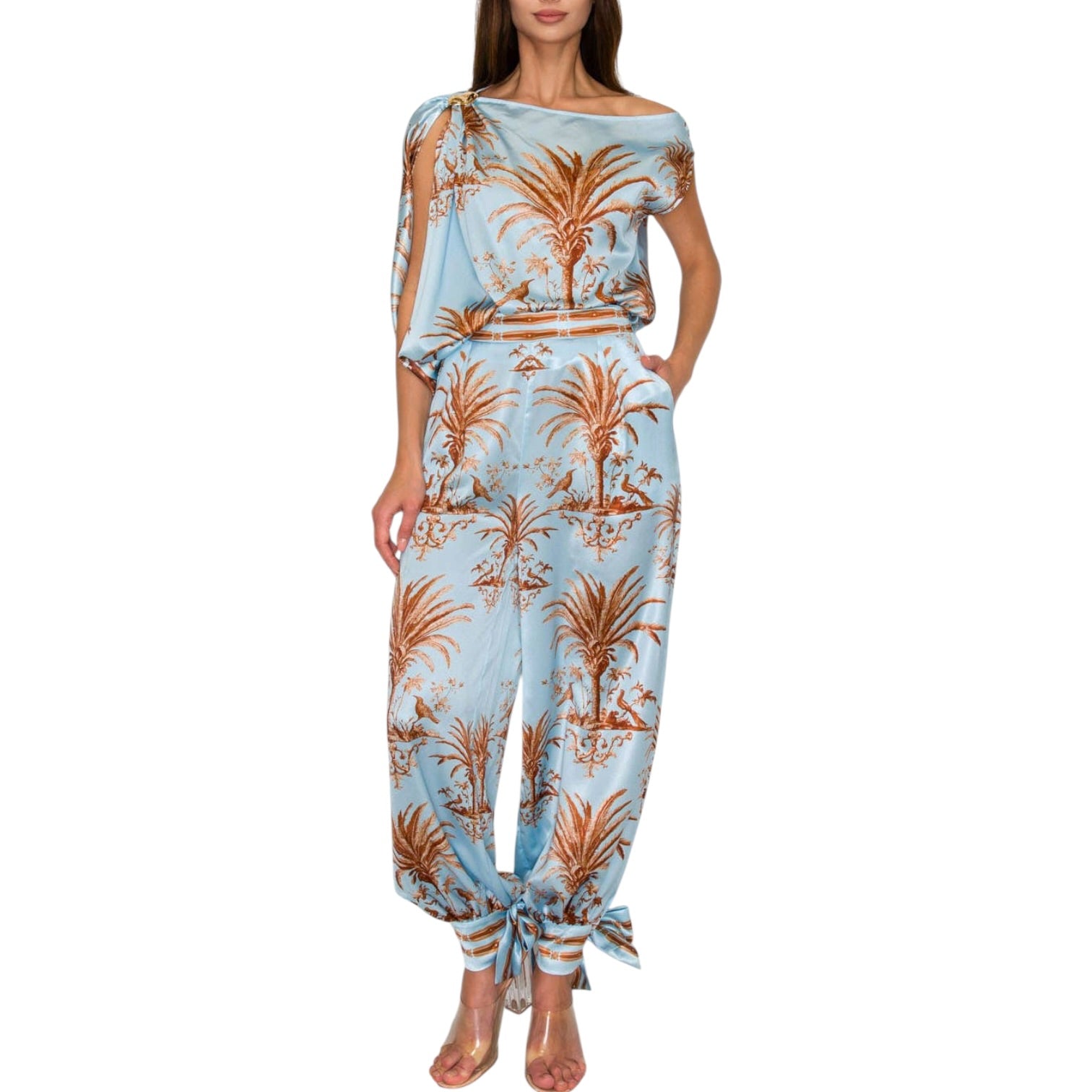 Woman wearing a light blue jumpsuit with palm tree pattern on a white background