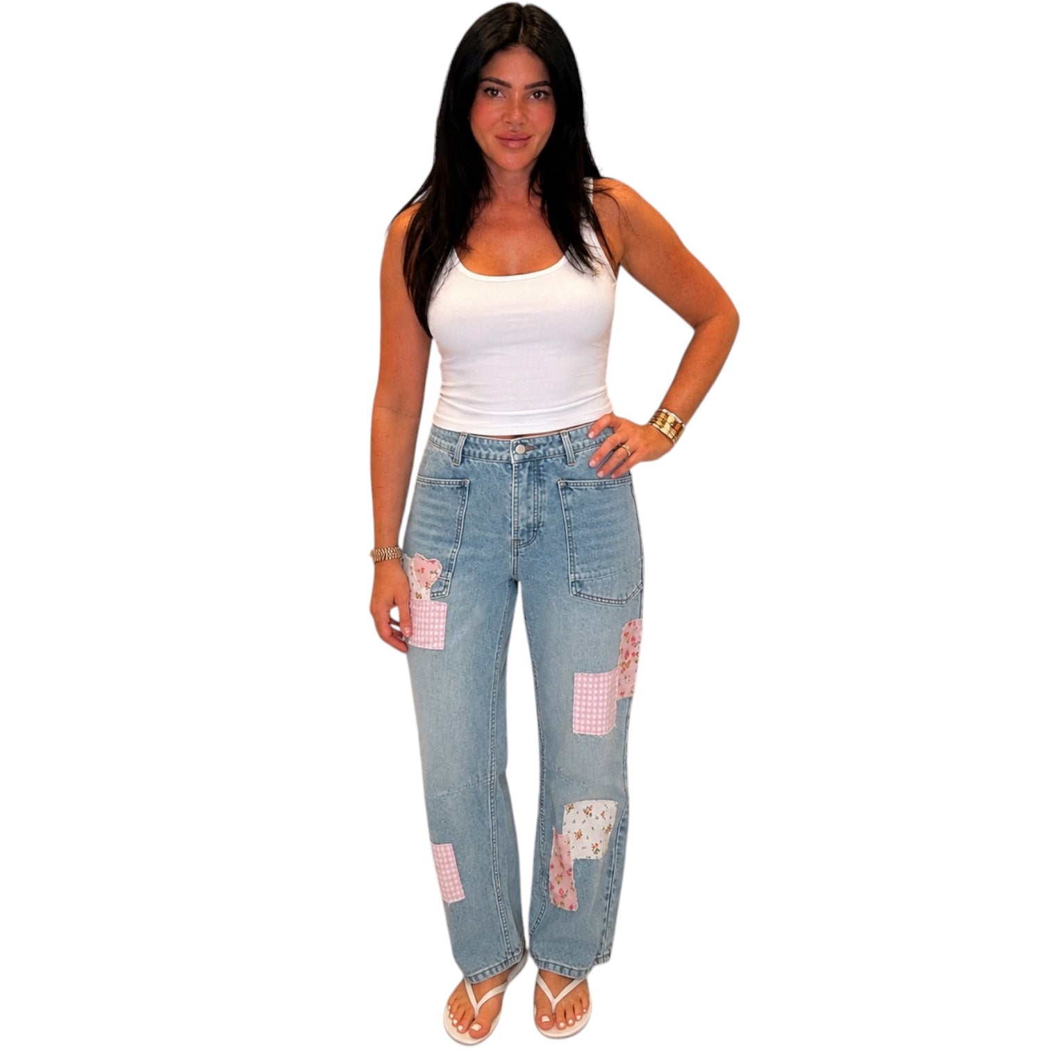 Woman wearing a white tank top and blue jeans with patchwork design on a white background