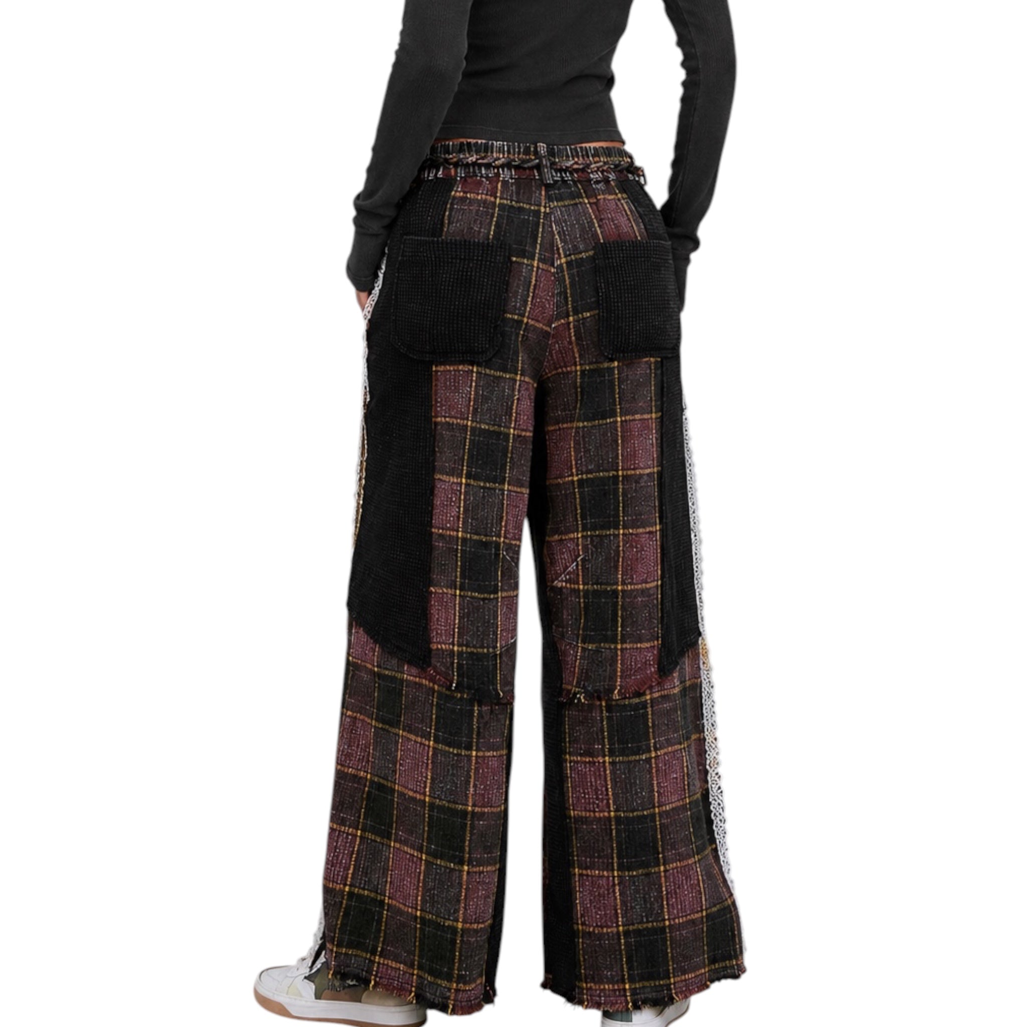 A person shown from the back wearing wide-leg patchwork pants with a plaid pattern in black, burgundy, and gold, featuring solid black patch pockets and a black corduroy back panel, paired with a black long-sleeve top and white sneakers.