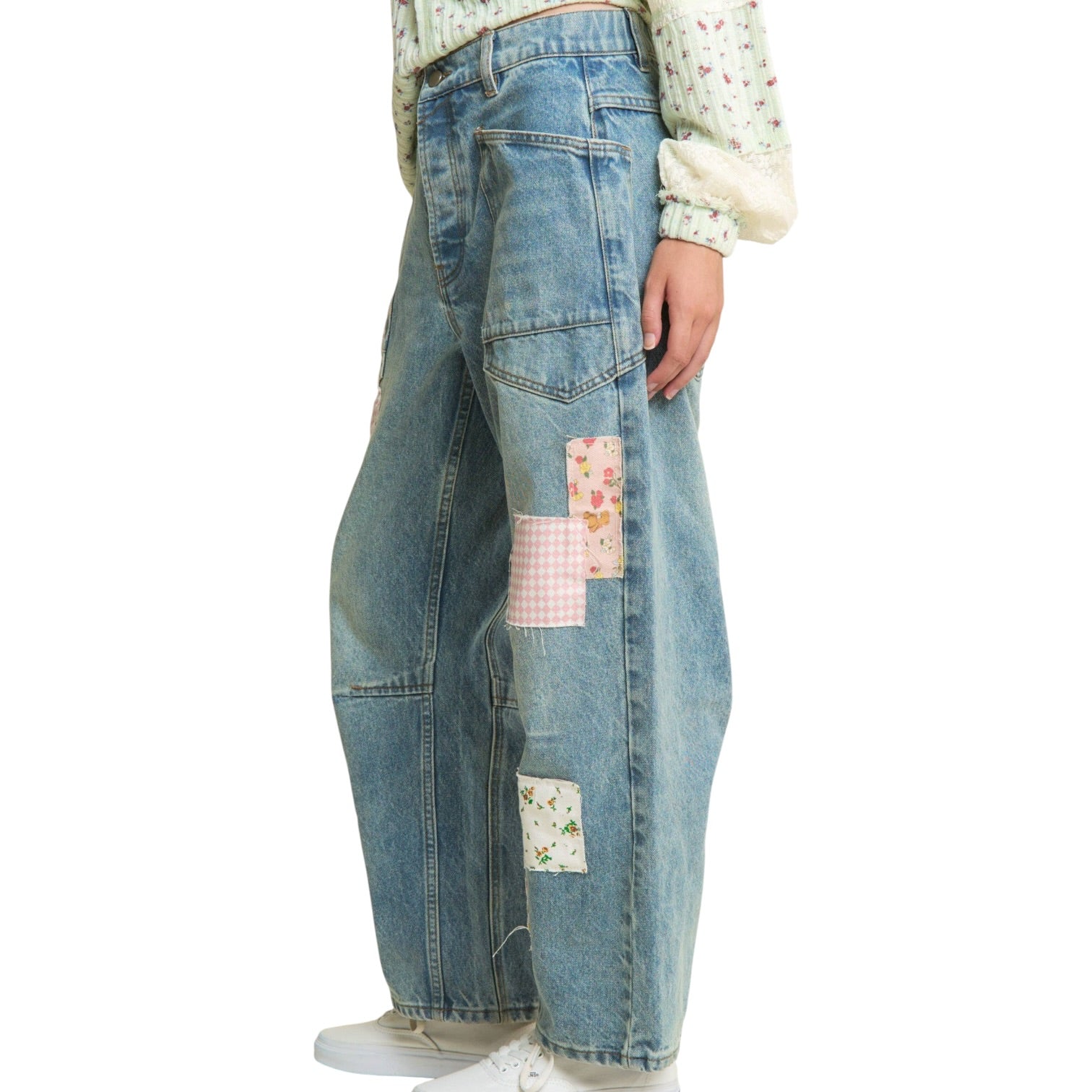 Blue jeans with patchwork design worn by a person on a white background