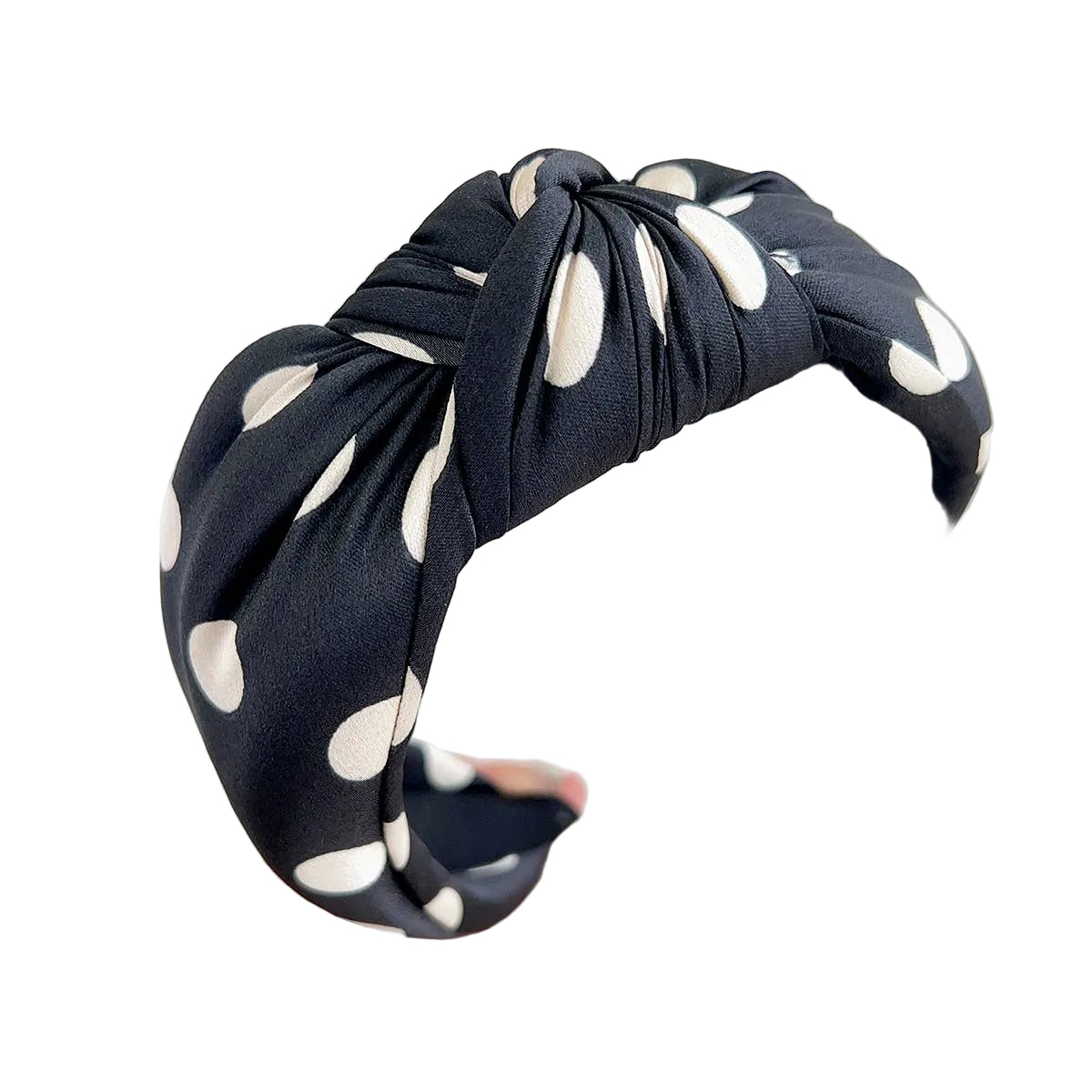 Black headband with white polka dots held by a hand against a light background