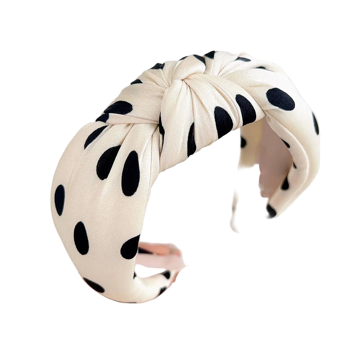 Polka dot headband held by a hand against a light gray background