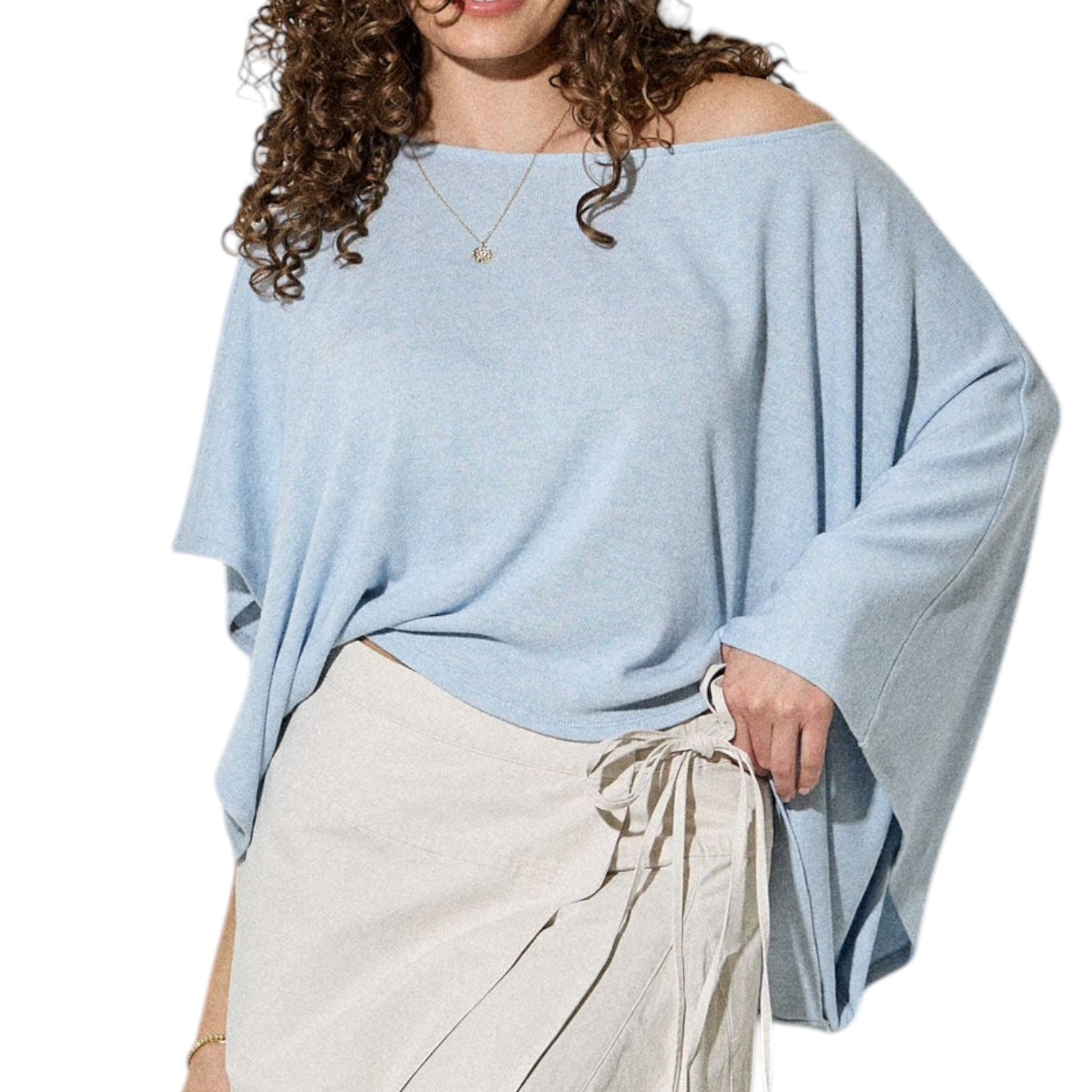 Woman wearing a light blue oversized sweater with beige pants on a white background