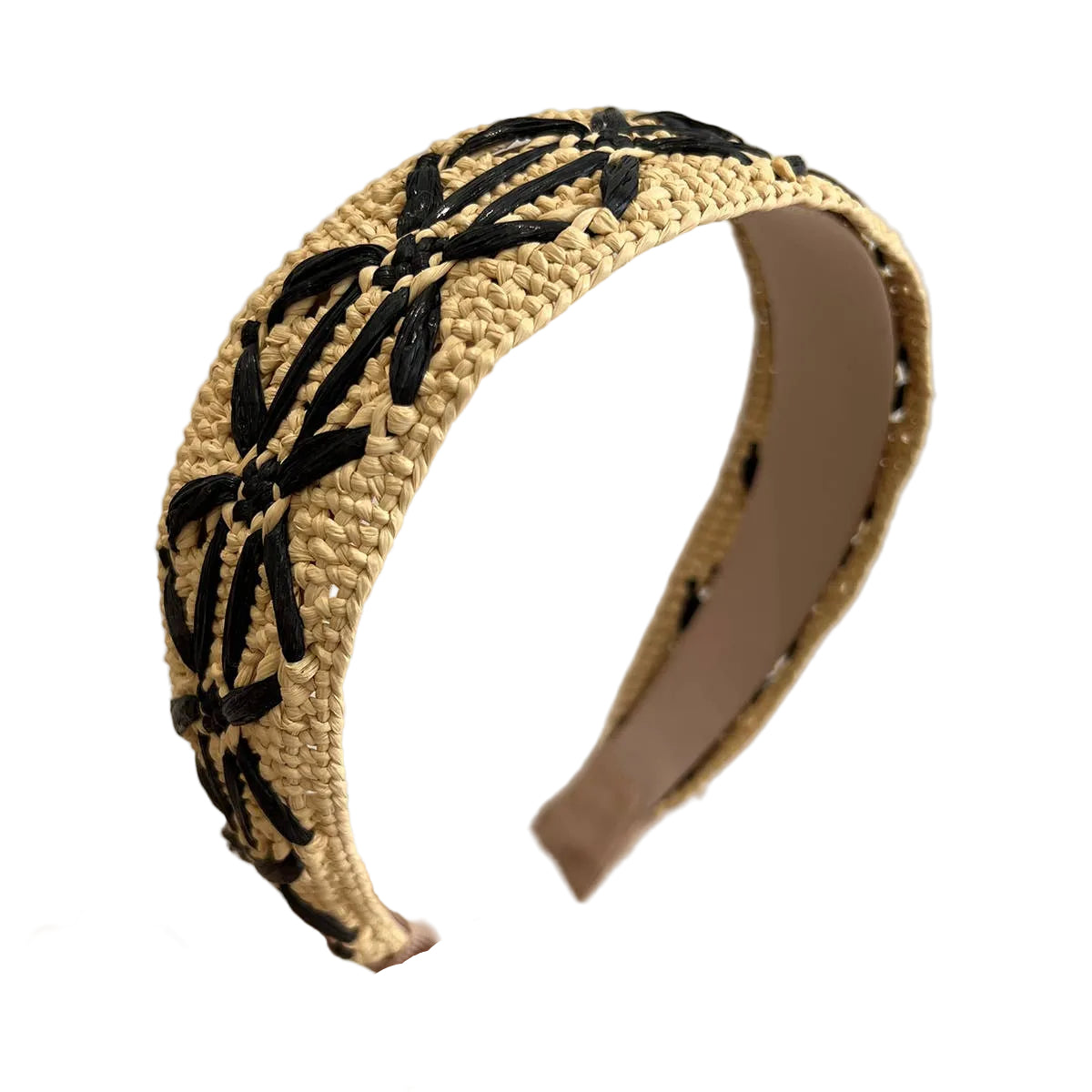 Raffia headband with black woven design held by a hand against a neutral background