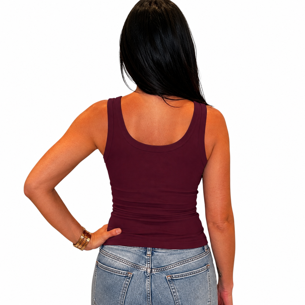 A woman shown from the back wearing a sleeveless scoop-neck tank top in deep burgundy, paired with light-wash blue jeans, against a plain white background.
