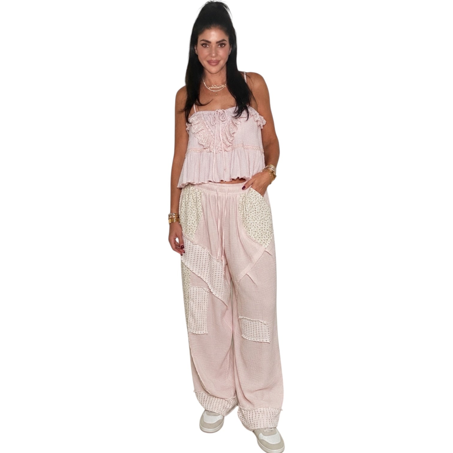 Woman wearing a light pink top and pants on a white background
