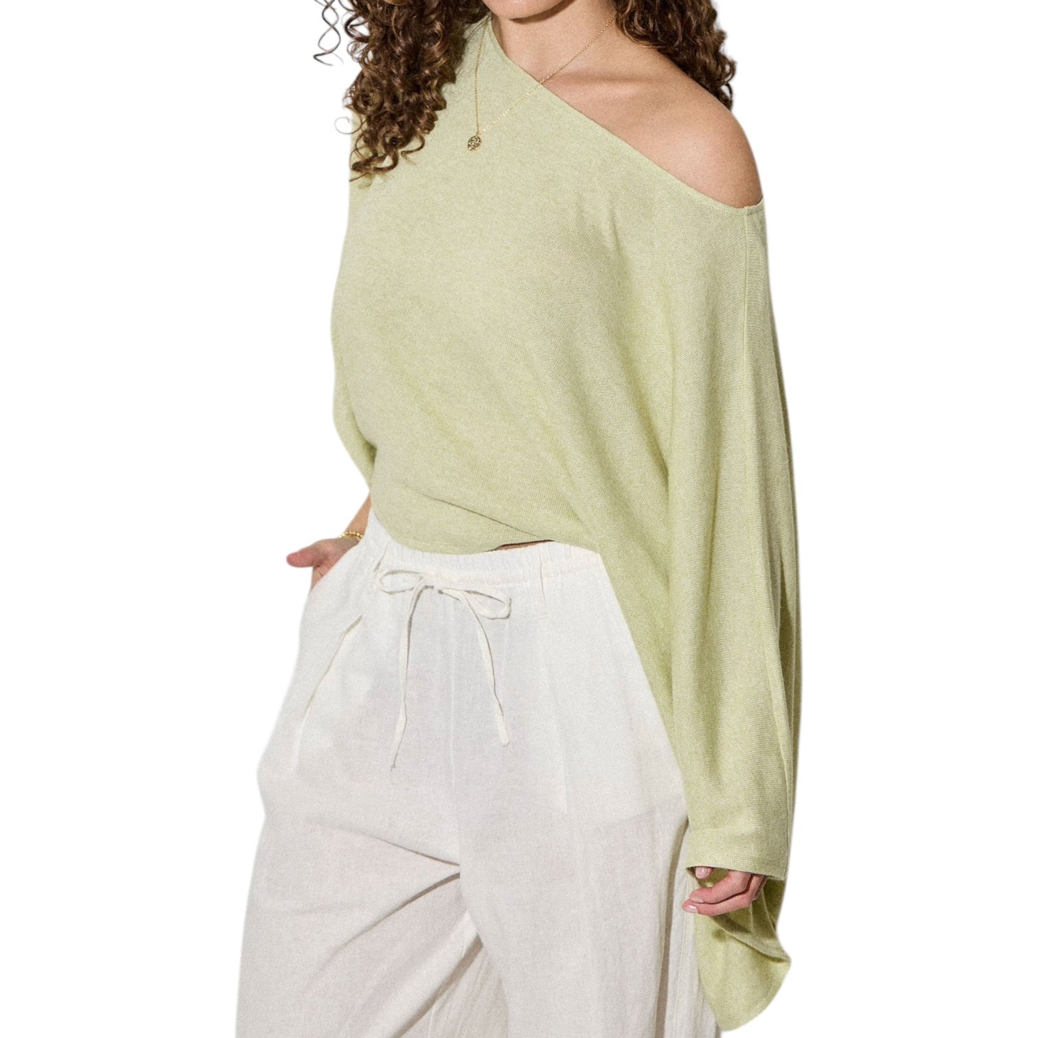 Woman wearing a light green off-shoulder top and white pants on a white background