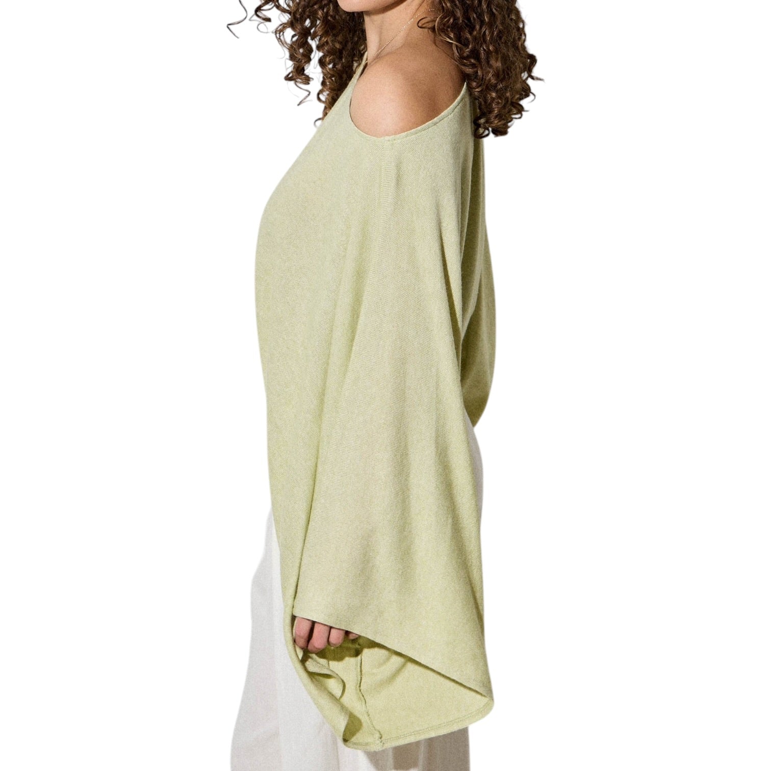 Woman wearing a light green off-shoulder top and white pants on a white background