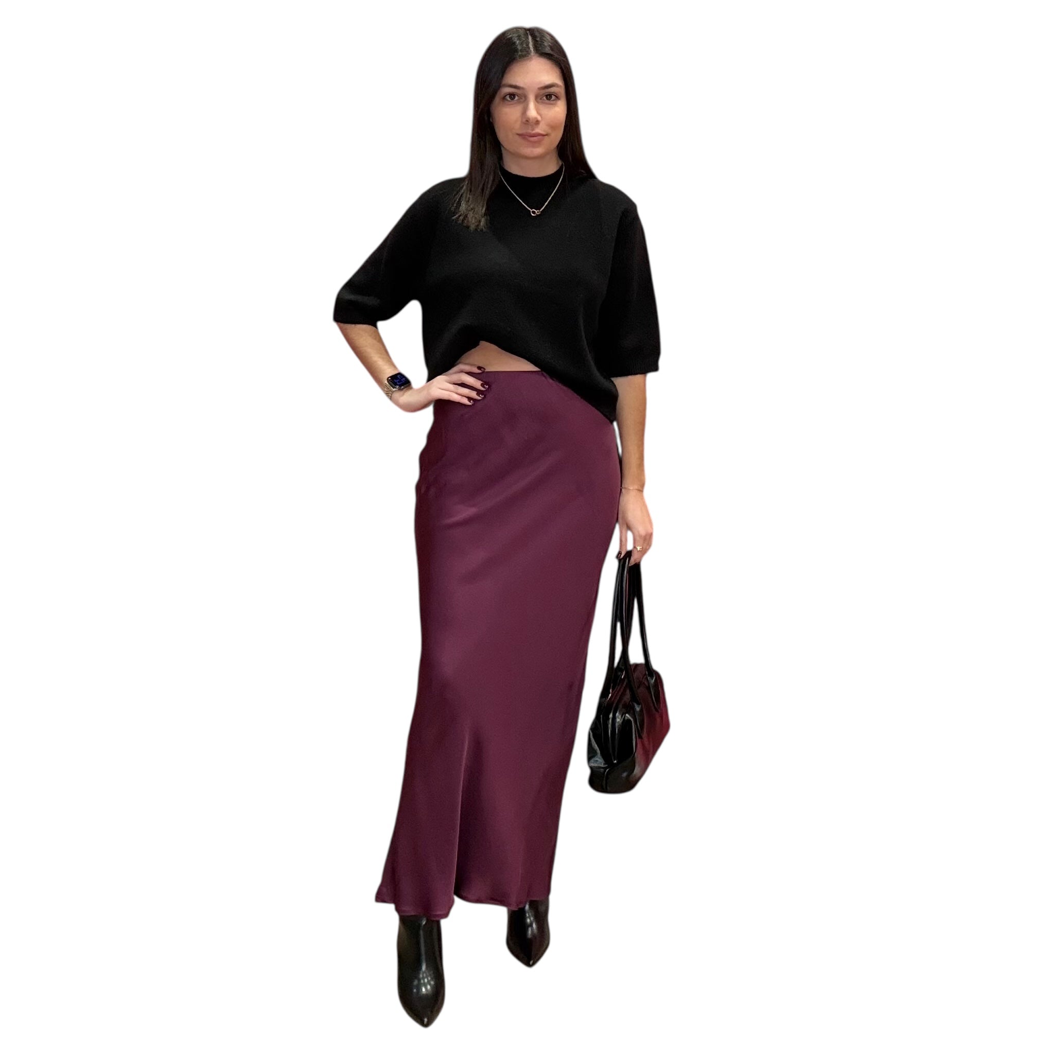 Woman wearing a black top and burgundy skirt holding a black handbag on a white background