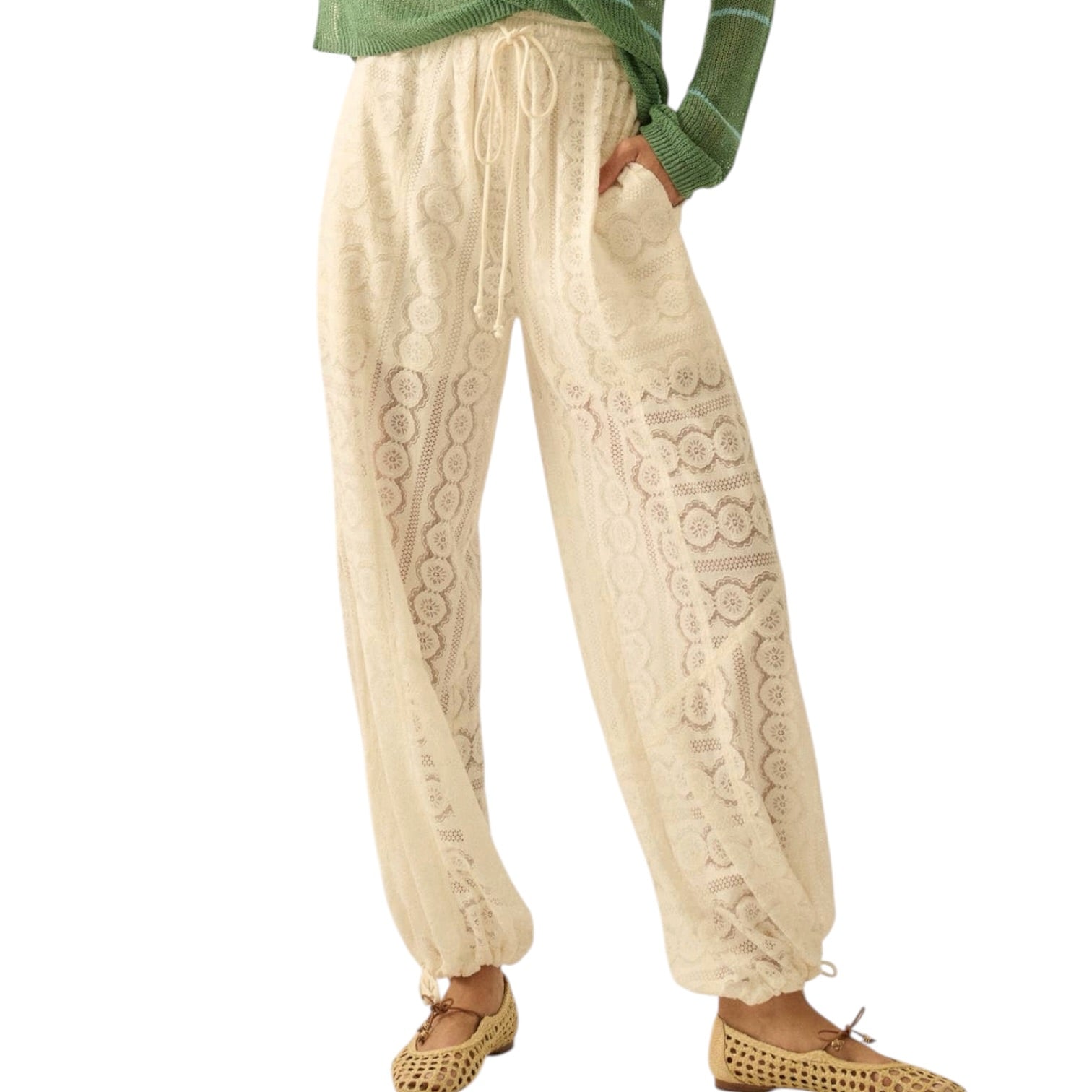 Beige embroidered pants worn with a green top on a white background
