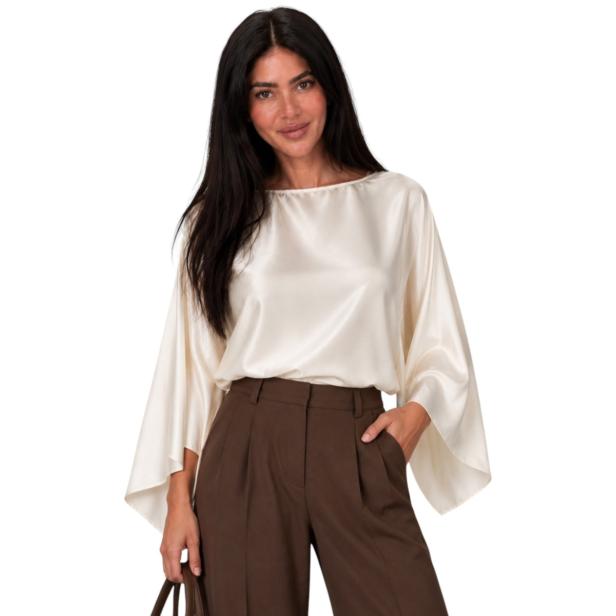 A woman modeling a cream satin blouse with wide bell sleeves and brown high-waisted trousers, photographed against a plain white background.