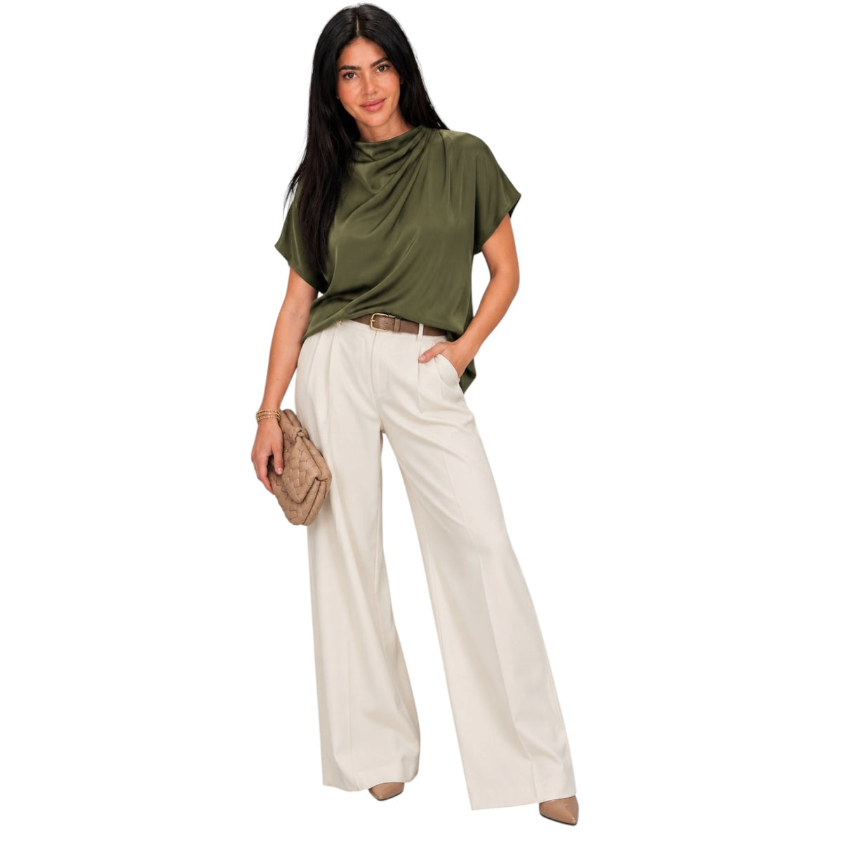 A woman modeling a short-sleeve olive green draped top and high-waisted off-white wide-leg trousers, styled with a brown belt and holding a beige clutch bag against a plain white background.