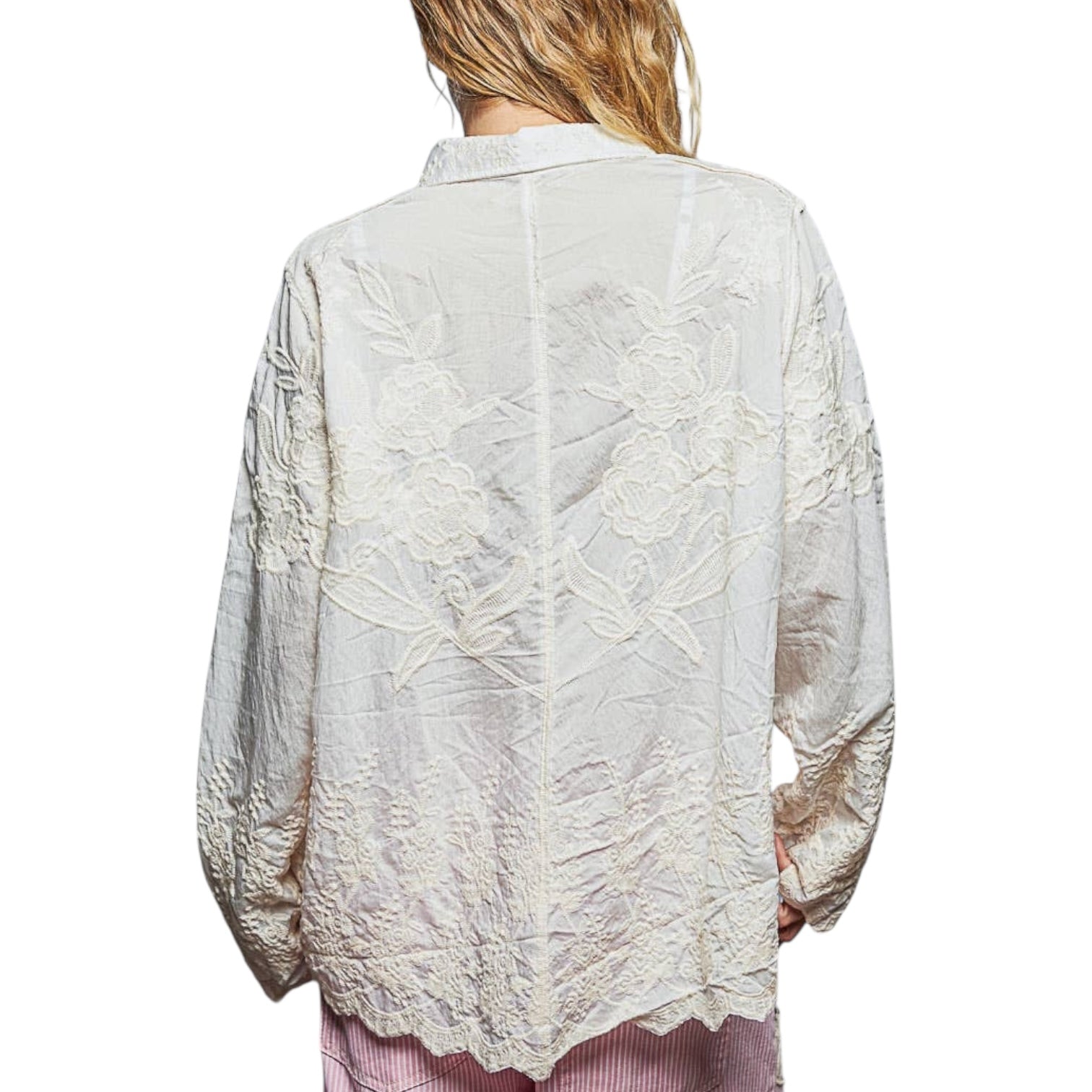 Light-colored lace blouse worn by a person on a white background