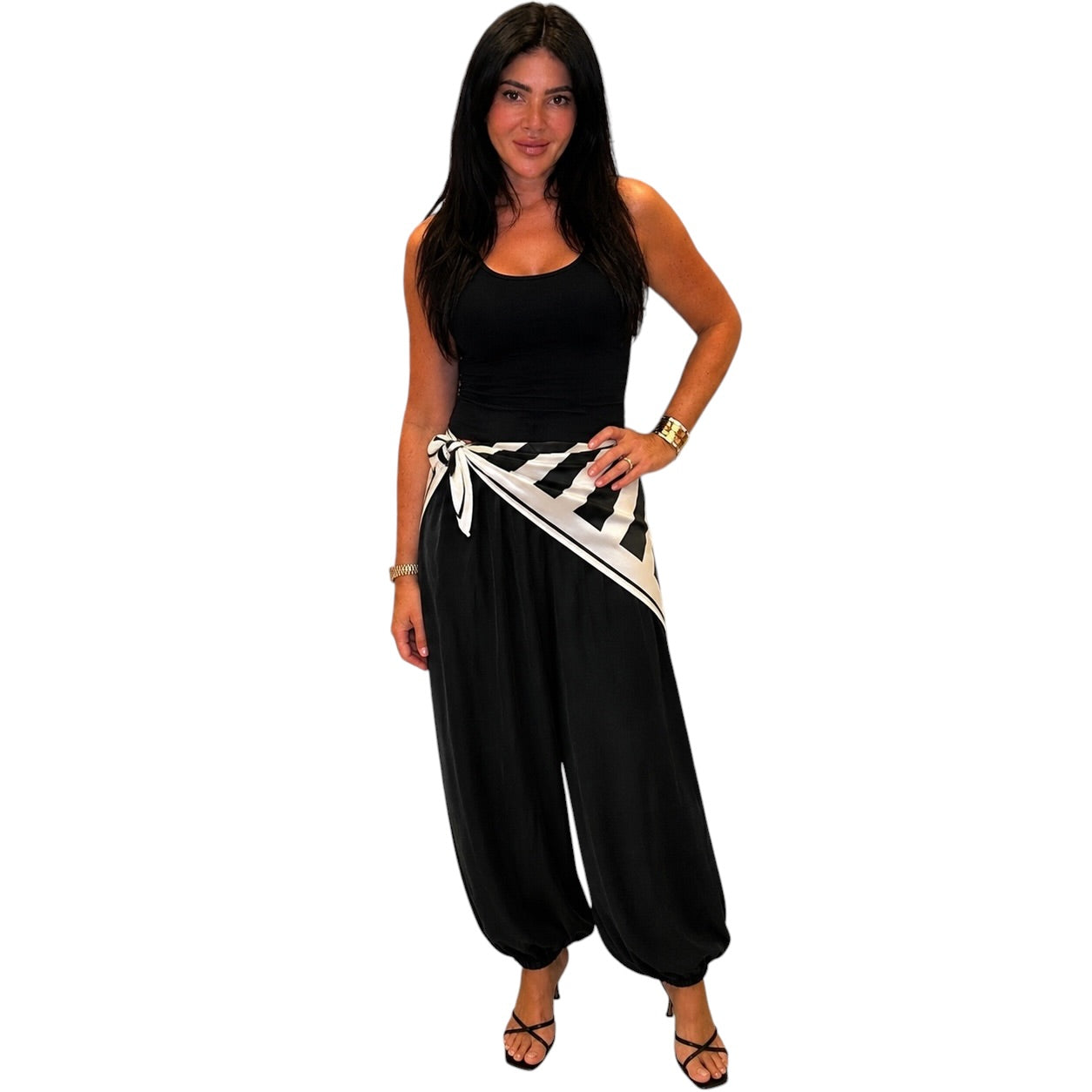 Woman wearing a black sleeveless top and wide-leg pants with a zebra-striped belt on a white background