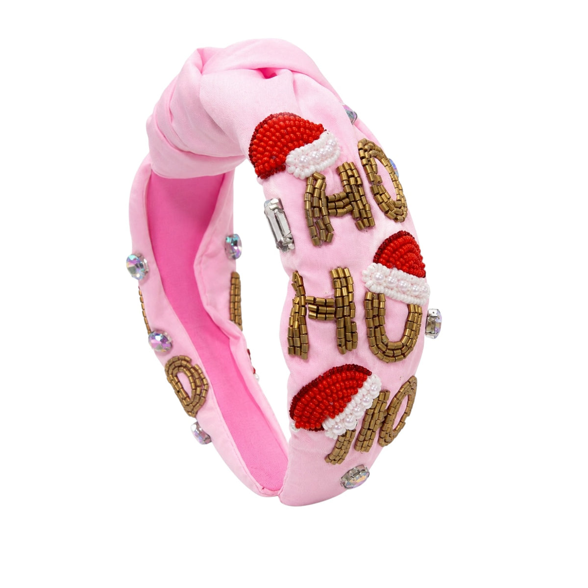 A pink knotted fabric headband decorated with red and white Santa hat embellishments, gold beaded letters spelling 'HO HO HO', and small rhinestone accents, shown on a plain white background.