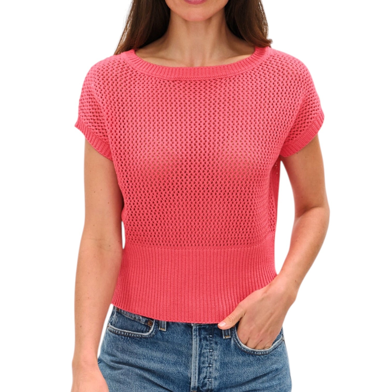 Woman wearing a pink knit top and blue jeans on a white background