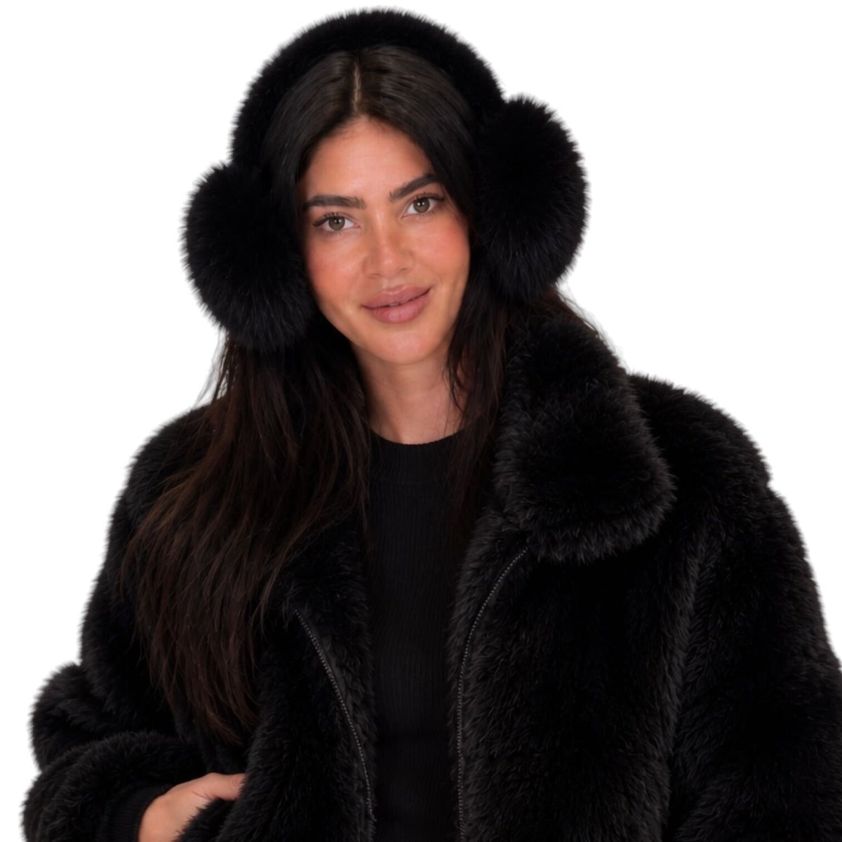 A woman wearing black faux fur earmuffs and a matching black faux fur coat over a black top, photographed against a solid white background.