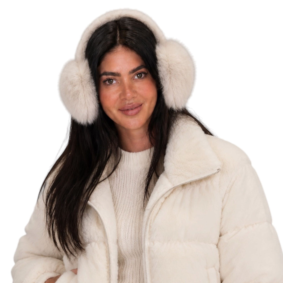 A woman wearing fluffy cream faux-fur earmuffs and a matching cream puffer jacket over a cream ribbed sweater, photographed against a plain white background.