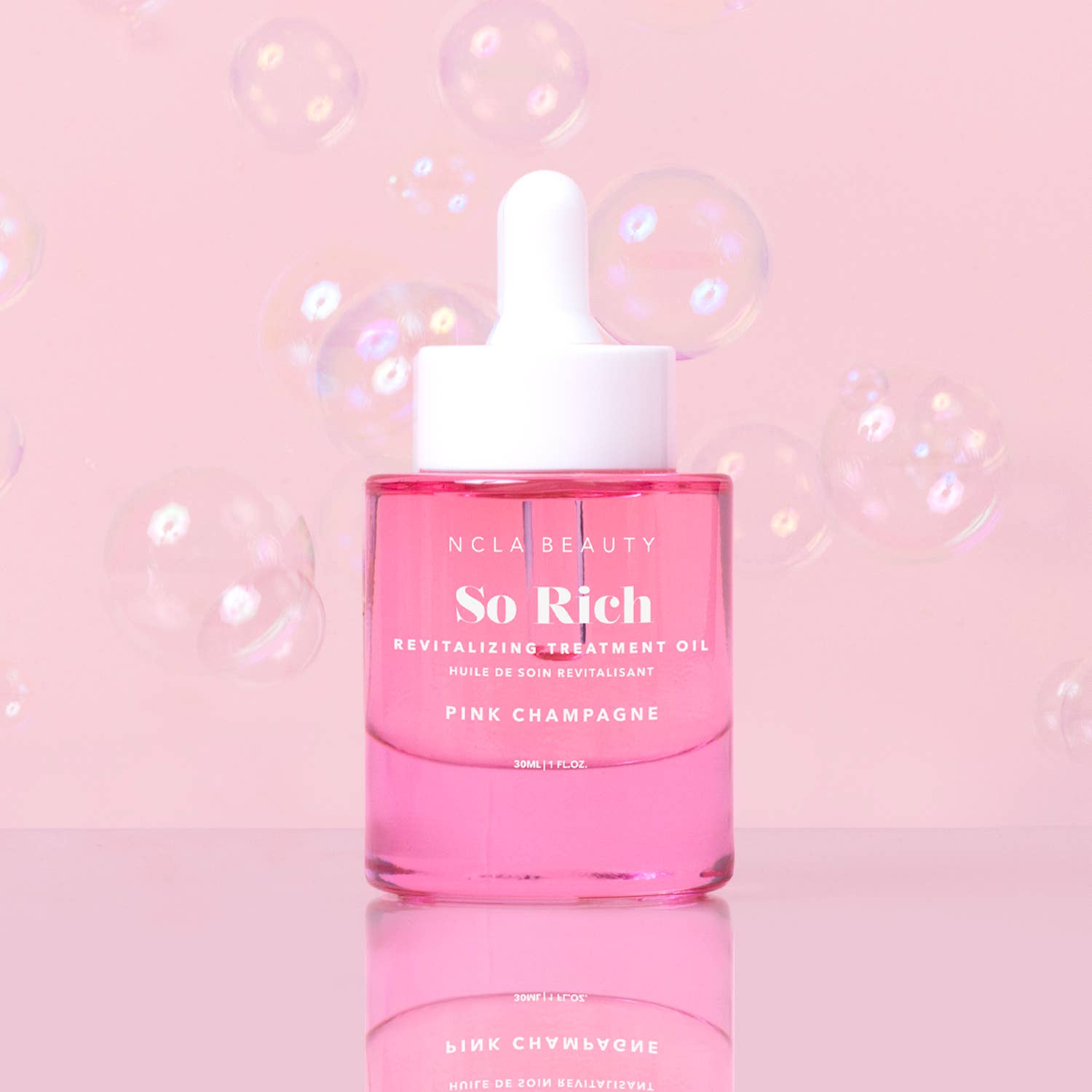 Pink bottle of NCLA Beauty 'So Rich' oil on a pink background with bubbles