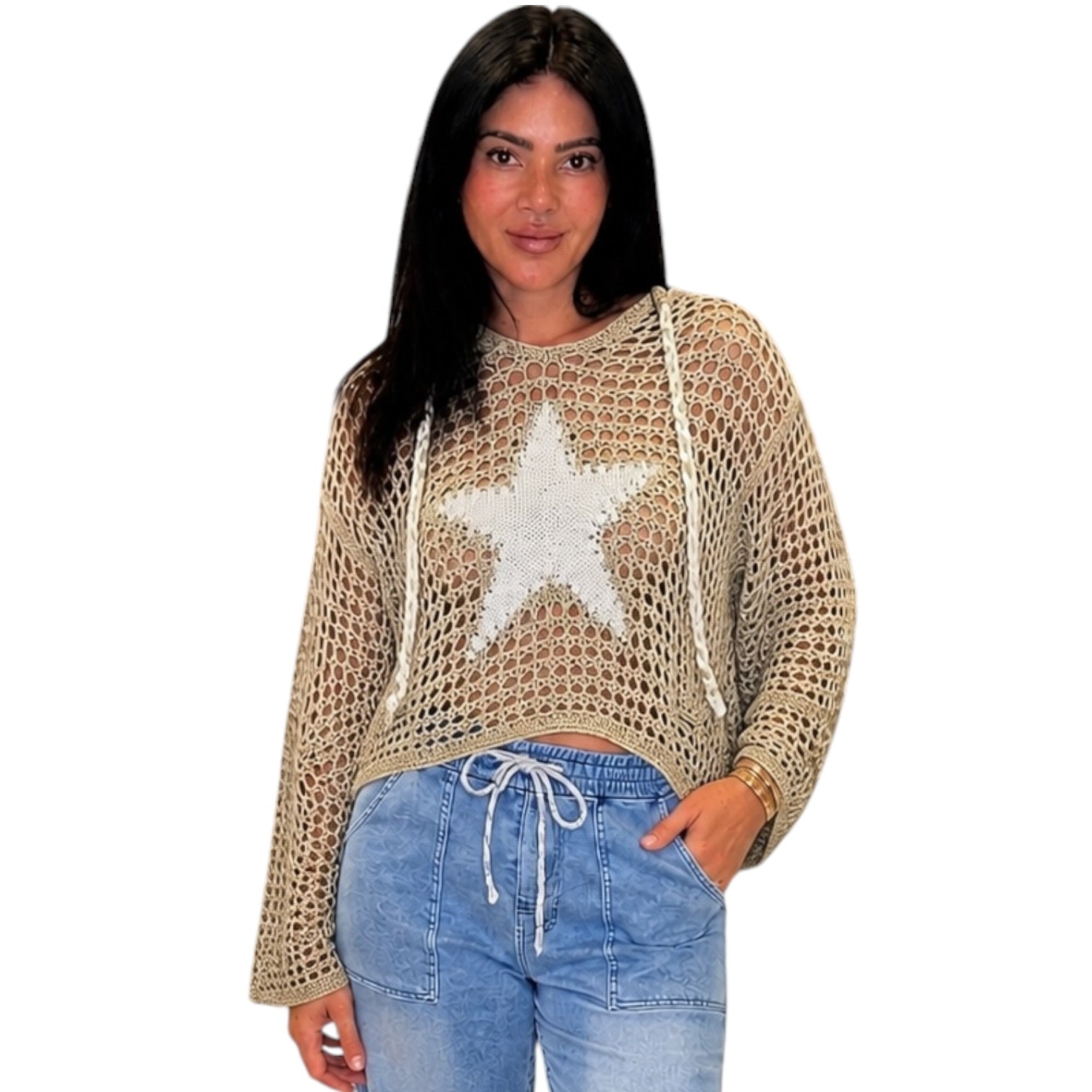 Woman wearing a olive crochet top with a star design and blue jeans on a white background