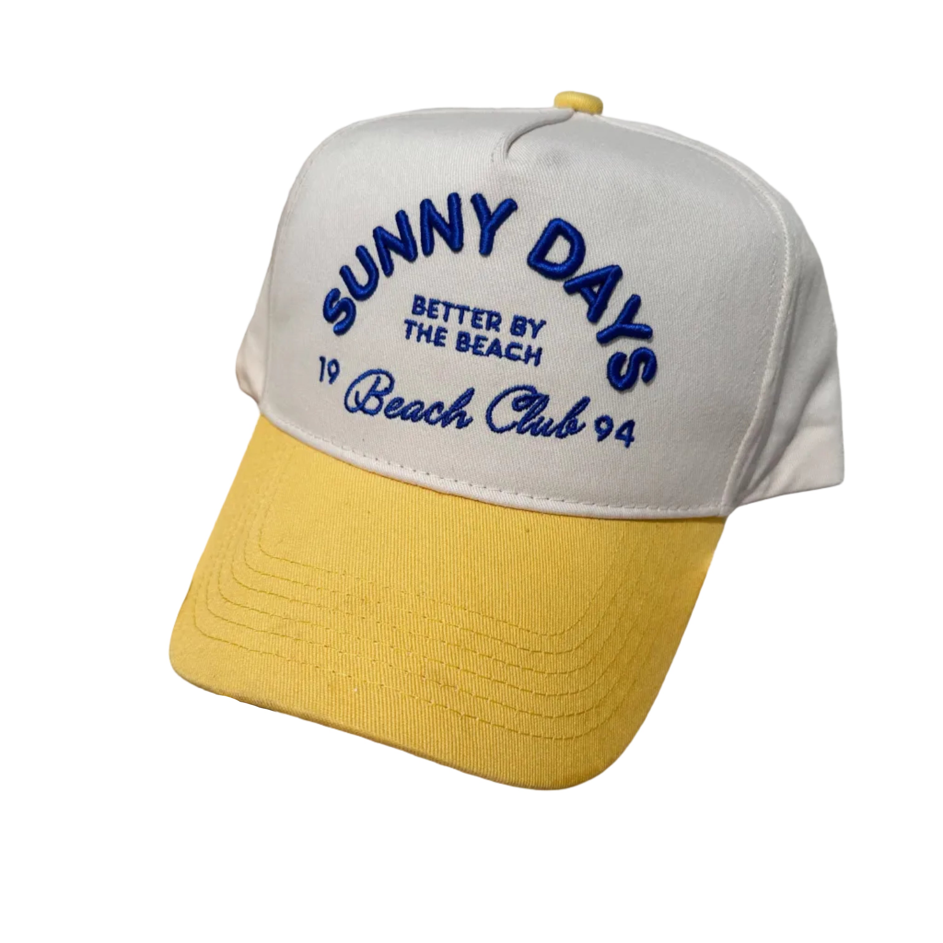 Beige and yellow cap with 'Sunny Days' text on a beach setting with sunglasses and a drink.