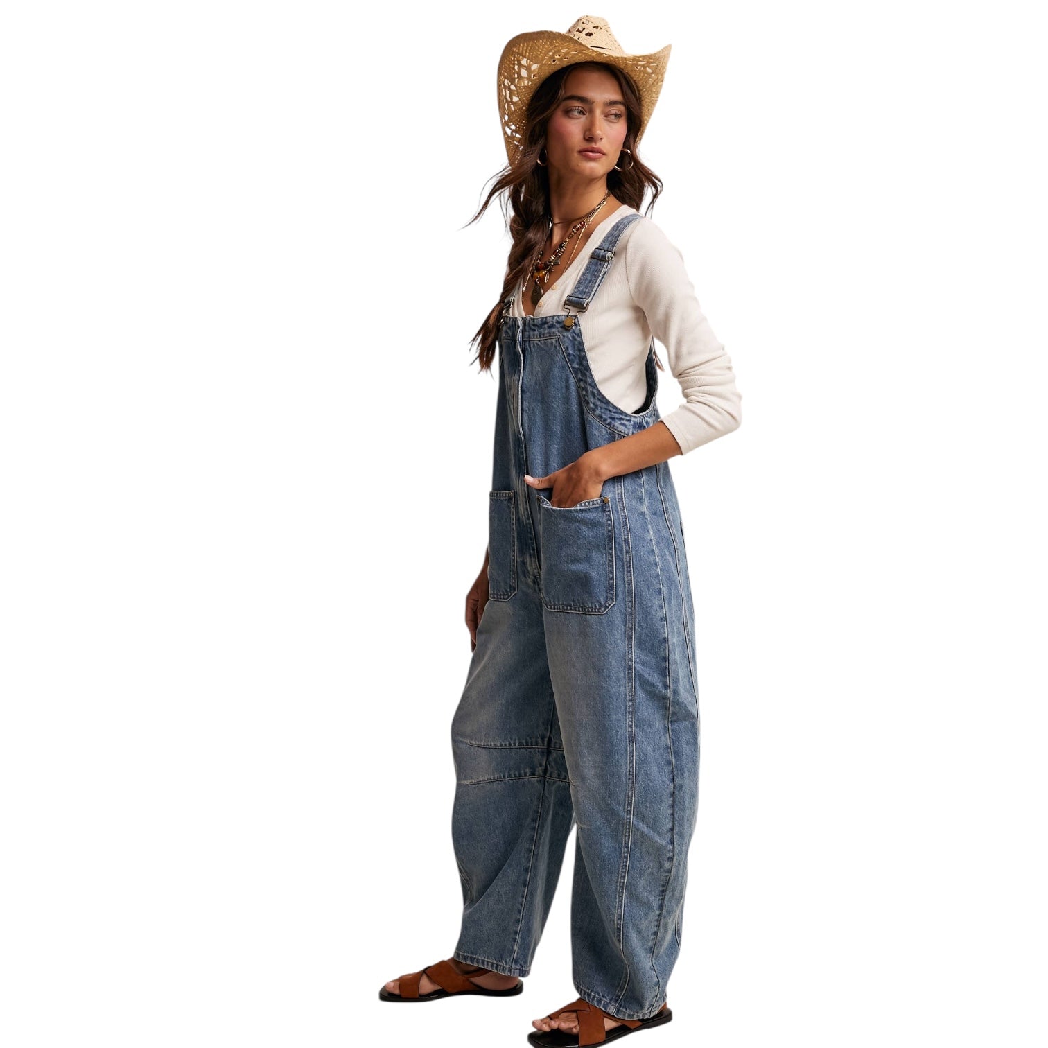 Woman wearing denim overalls and a straw hat on a white background