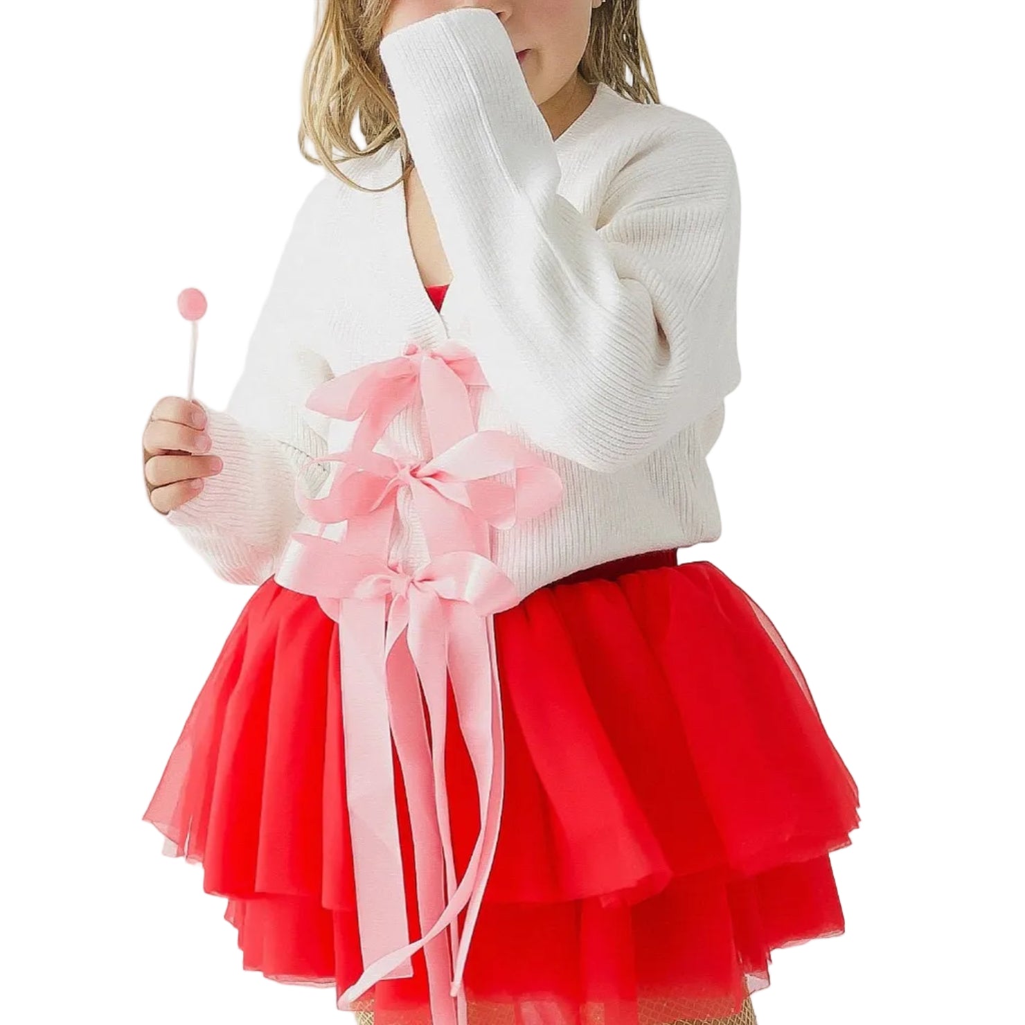 Young girl in a red skirt and white sweater holding a pink flower against a white background