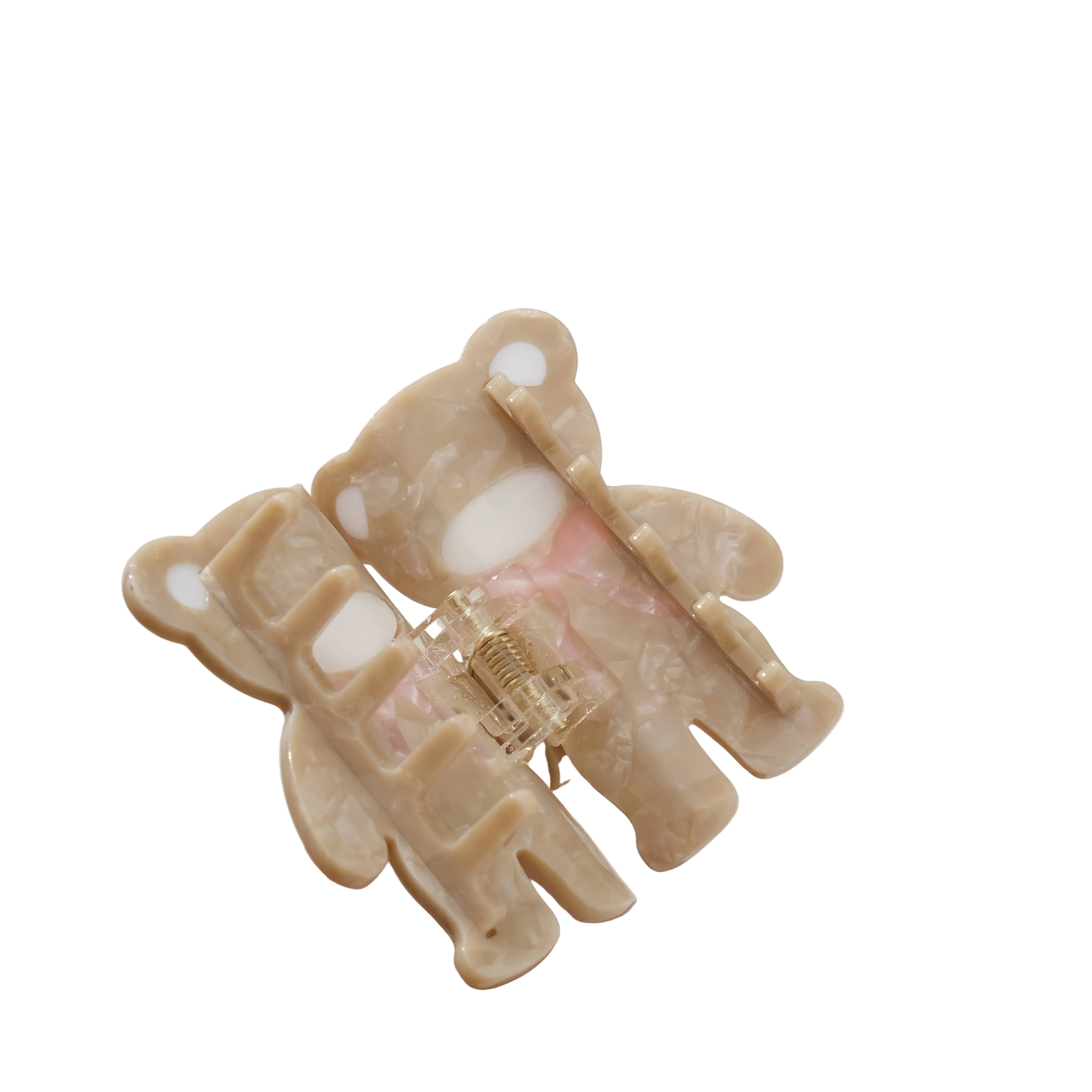 Beige hair clip with a clear plastic clip held by a hand on a light background