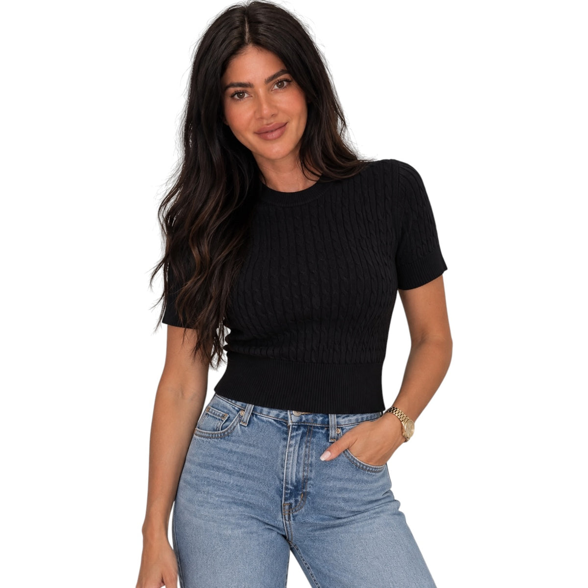 A woman modeling a black short-sleeve ribbed knit top with light blue jeans against a plain white background.