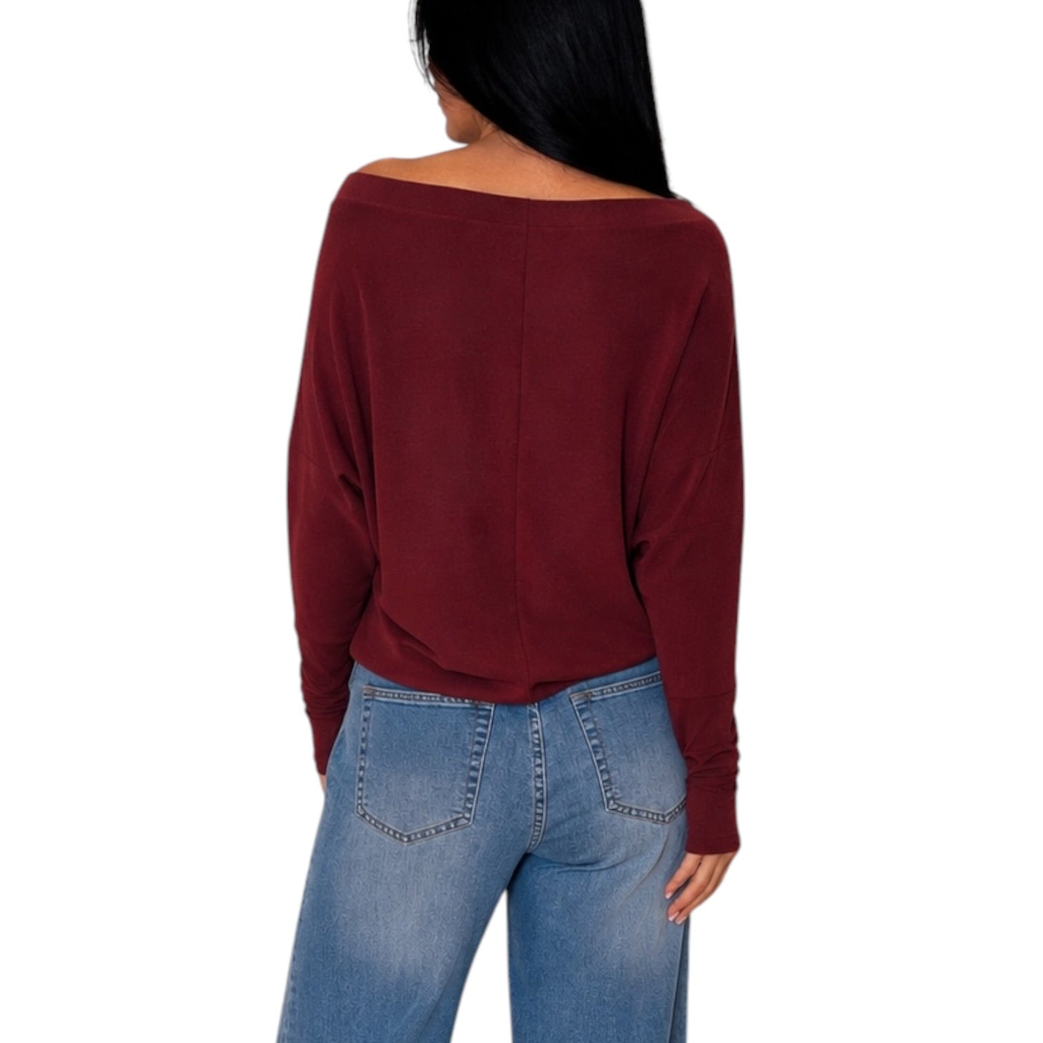 A woman shown from the back wearing a loose, off-the-shoulder long-sleeve top in burgundy and light blue jeans, set against a plain white background.