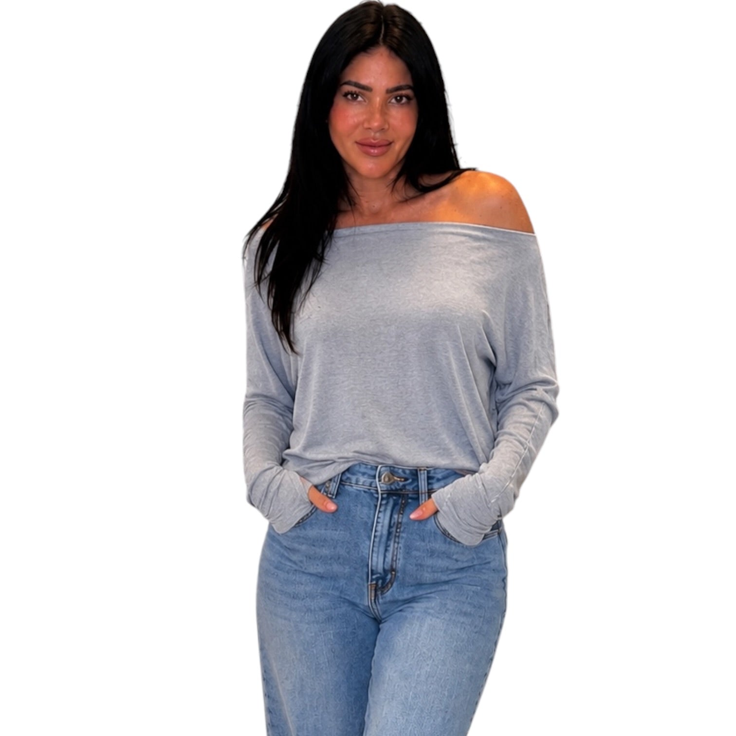 A woman modeling a light gray off-the-shoulder long-sleeve top with light-wash blue jeans against a plain white background.