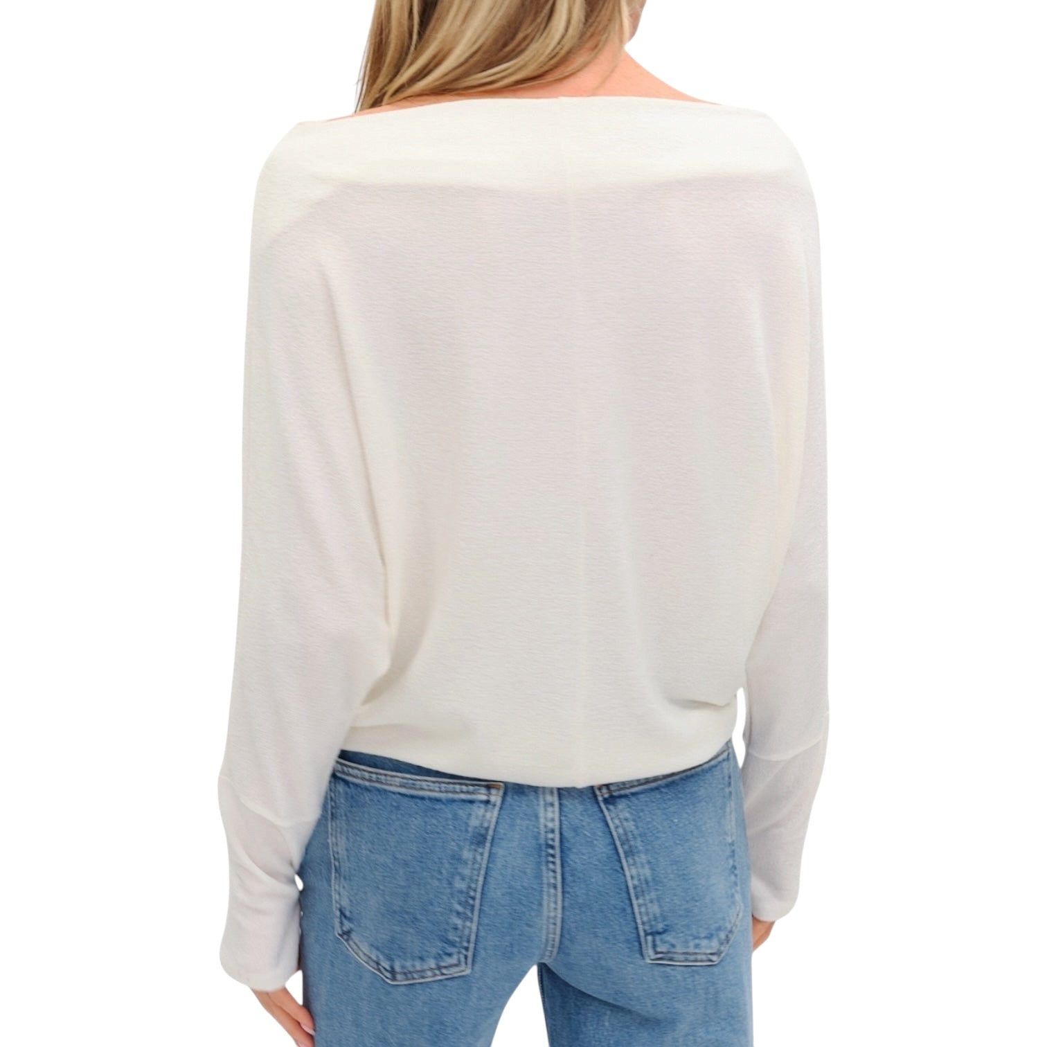 Person wearing a white long-sleeve top and blue jeans on a white background