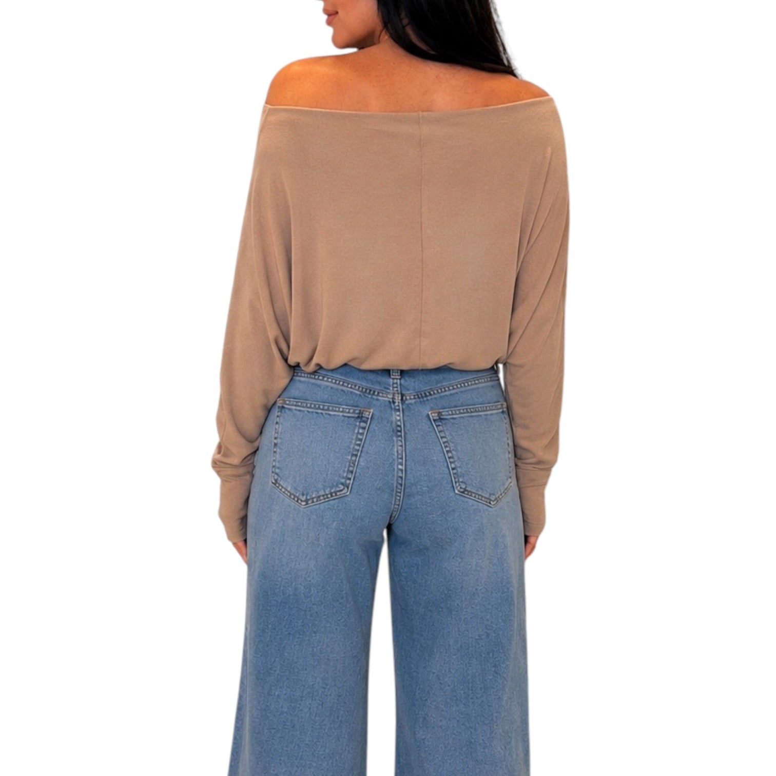 A woman shown from the back wearing a tan off-the-shoulder long-sleeve top and light blue wide-leg jeans against a plain white background.