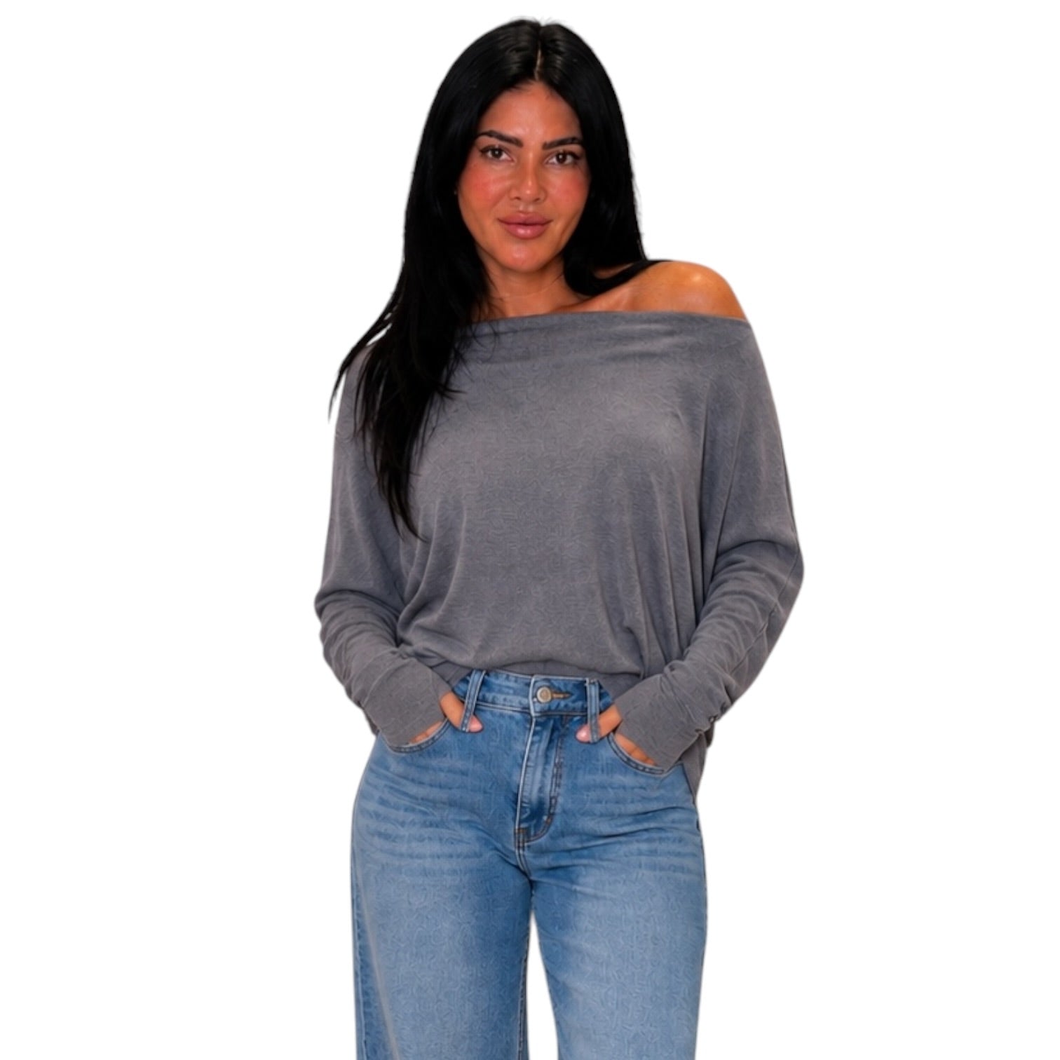 A woman modeling a gray off-the-shoulder long-sleeve top with blue jeans against a plain white background.