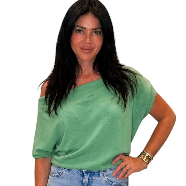 Woman wearing a green top and blue jeans on a white background