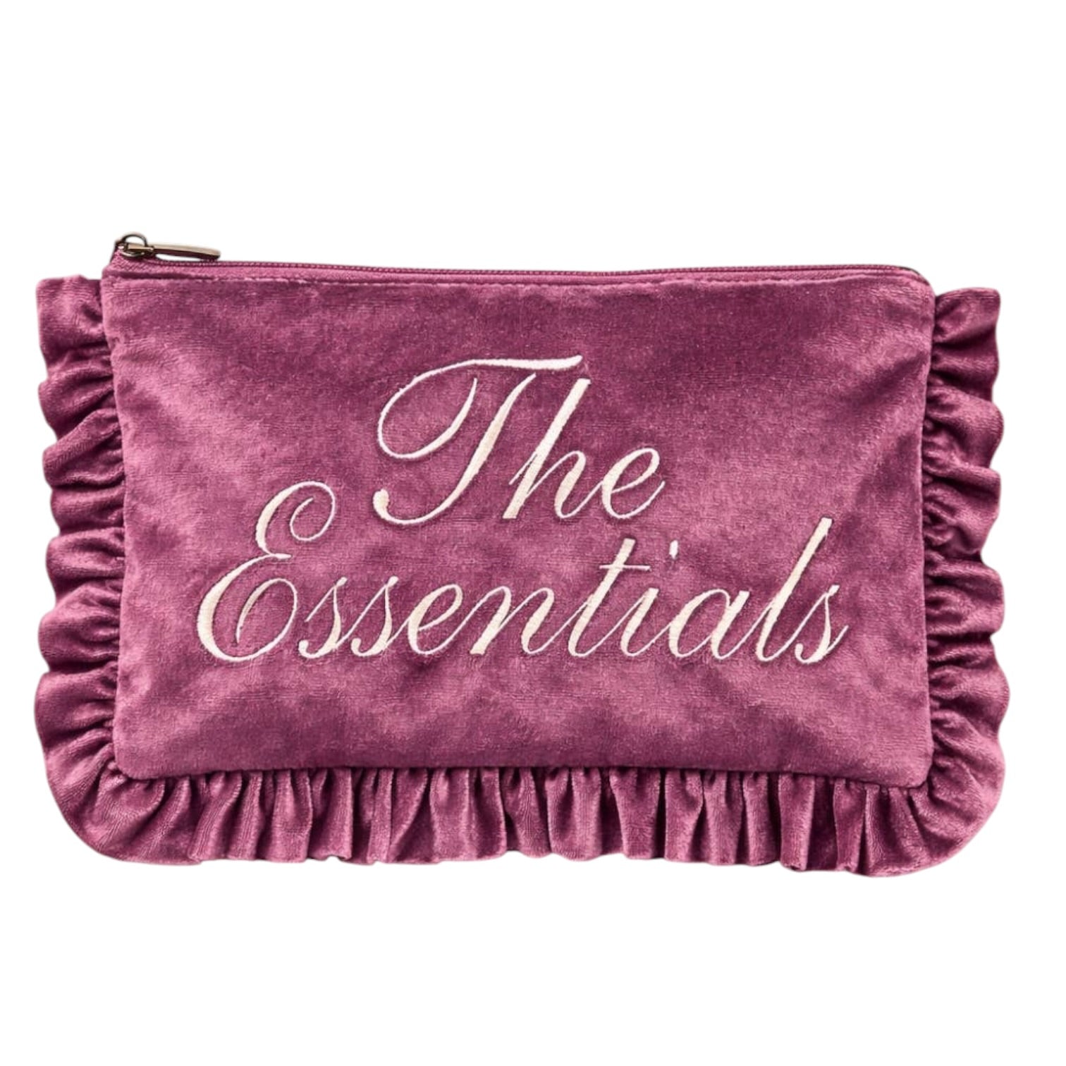A dusty rose velvet makeup pouch with 'The Essentials' embroidered in white script across the front, featuring ruffled trim along the edges and a top zipper.