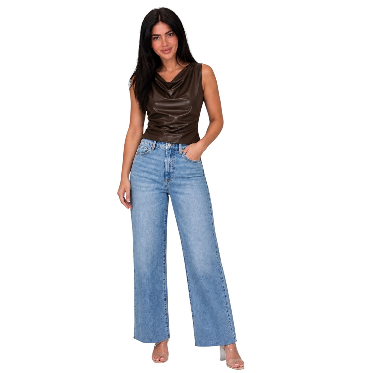 A woman modeling a pair of wide-leg light blue denim jeans with a brown satin sleeveless top, standing against a solid white background.