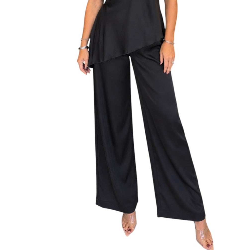 A woman modeling a black satin halter-neck top and matching wide-leg pants set against a plain white background.