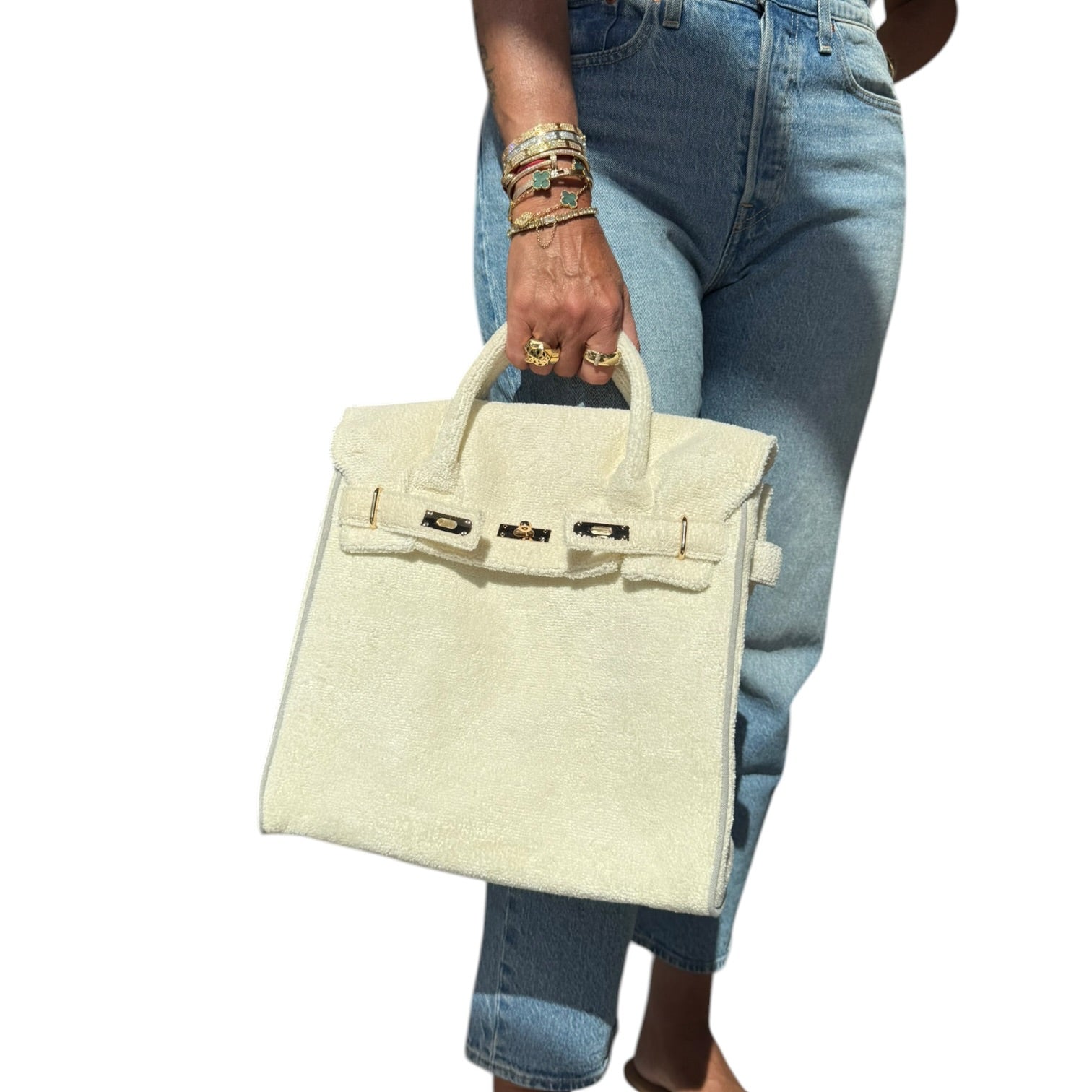 Person holding a off white terry handbag with blue jeans