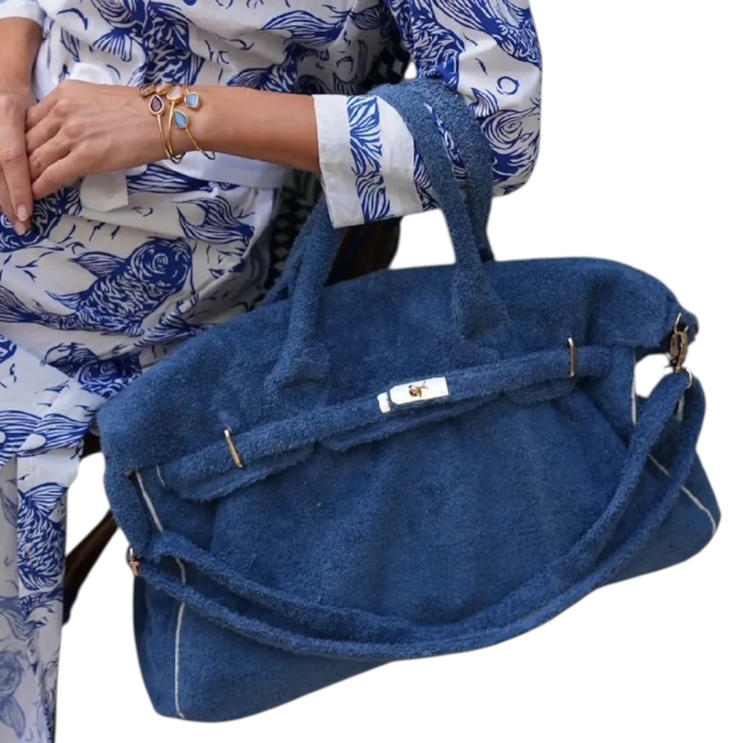 Blue textured handbag held by a person wearing a patterned outfit.