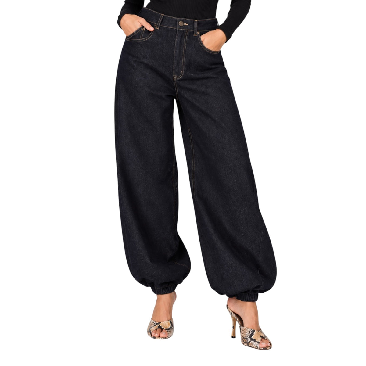A model wearing high-waisted, wide-leg dark wash denim pants with gathered cuffs, paired with a black long-sleeve top and metallic heeled sandals, shown against a plain white background.