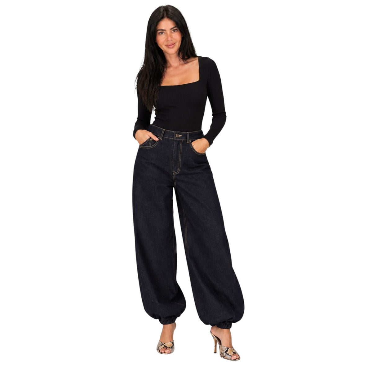 A woman modeling a black long-sleeve square-neck top and black wide-leg balloon-hem jeans with silver high-heeled sandals, set against a plain white background.