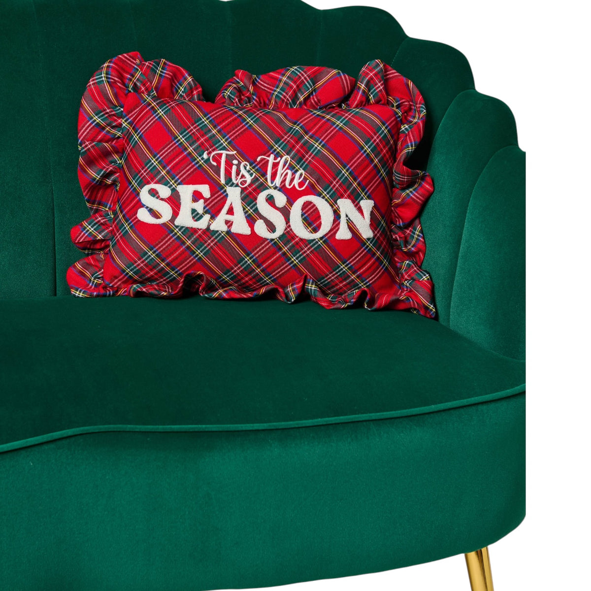 A red plaid ruffled throw pillow with the words 'Tis the SEASON' in white, displayed on a dark green velvet armchair.