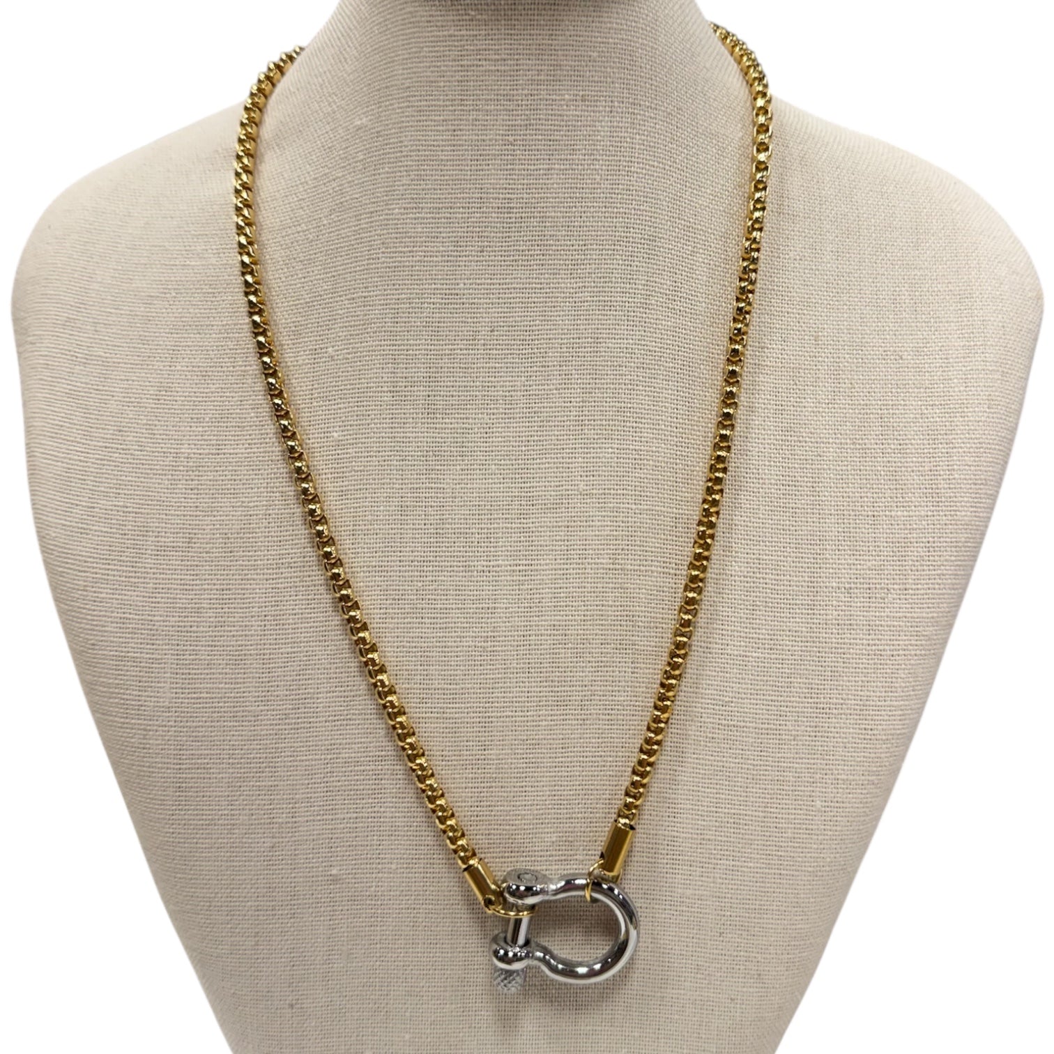 Gold chain necklace with a silver clasp on a mannequin bust.